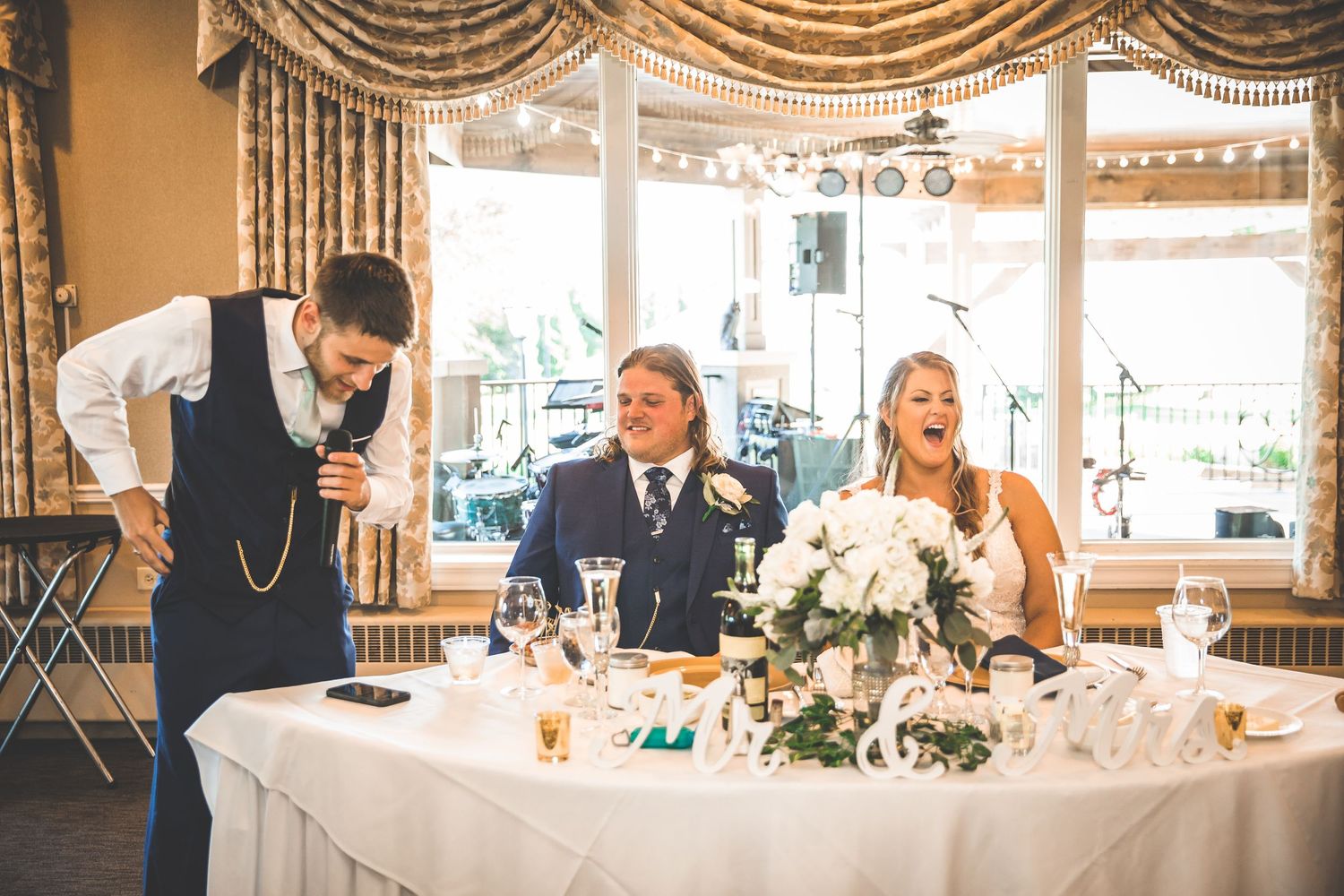 Elegant wedding reception venue with draped fabric decor and floral centerpieces on white tablecloths.