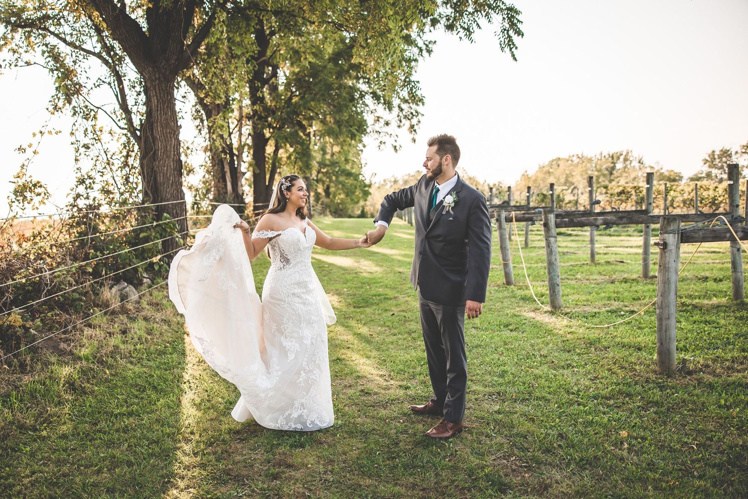 Romantic wedding portraits taken in a scenic outdoor setting with trees and fencing.