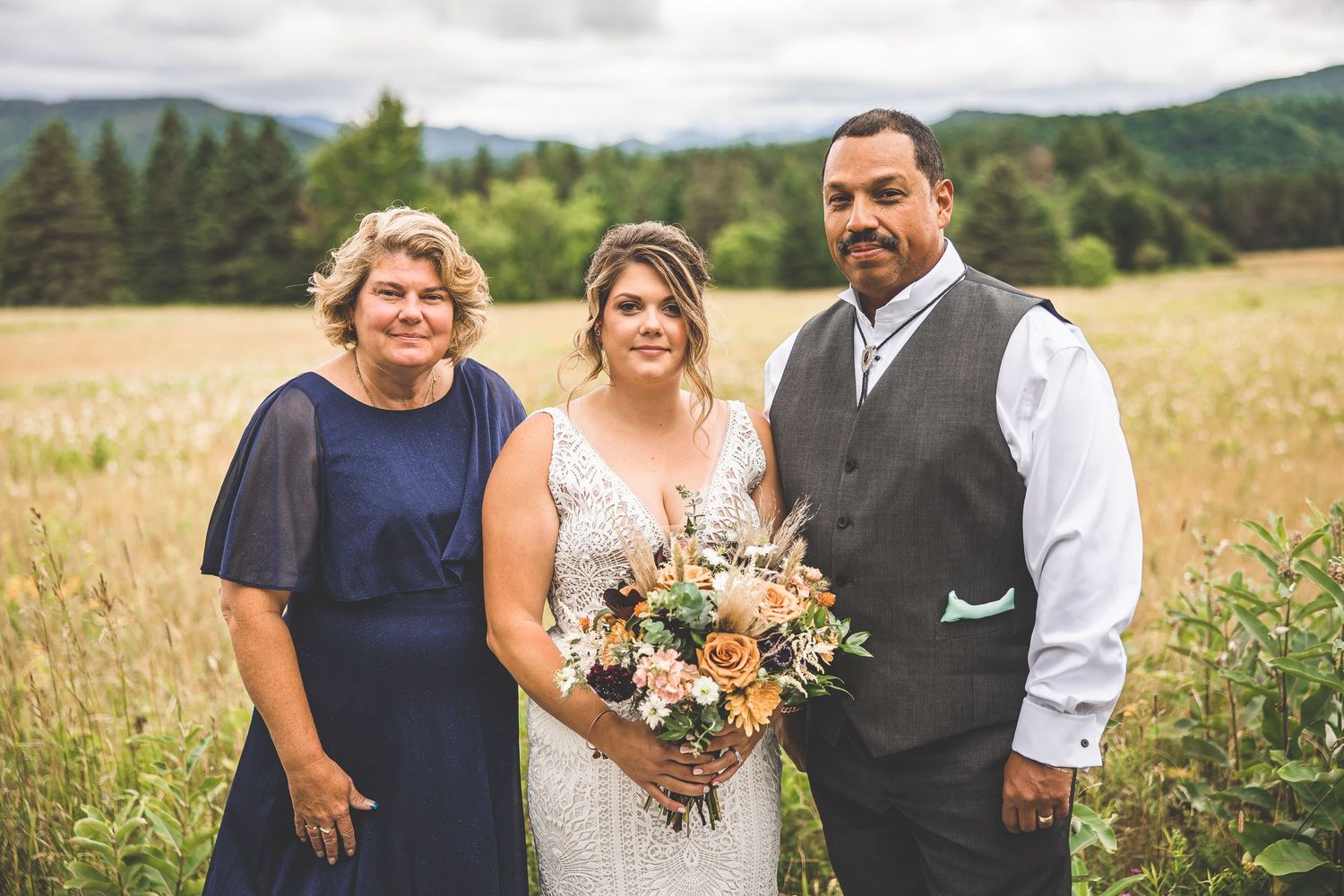 Wedding celebration group photo in a scenic mountain meadow.