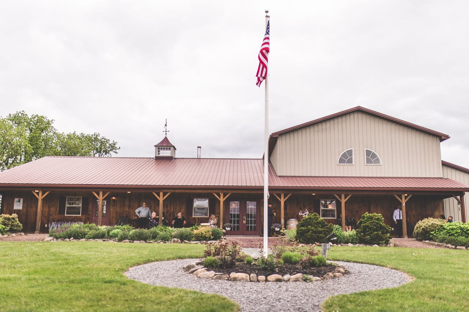 Exterior view of a modern barn-style wedding venue with landscaped grounds.