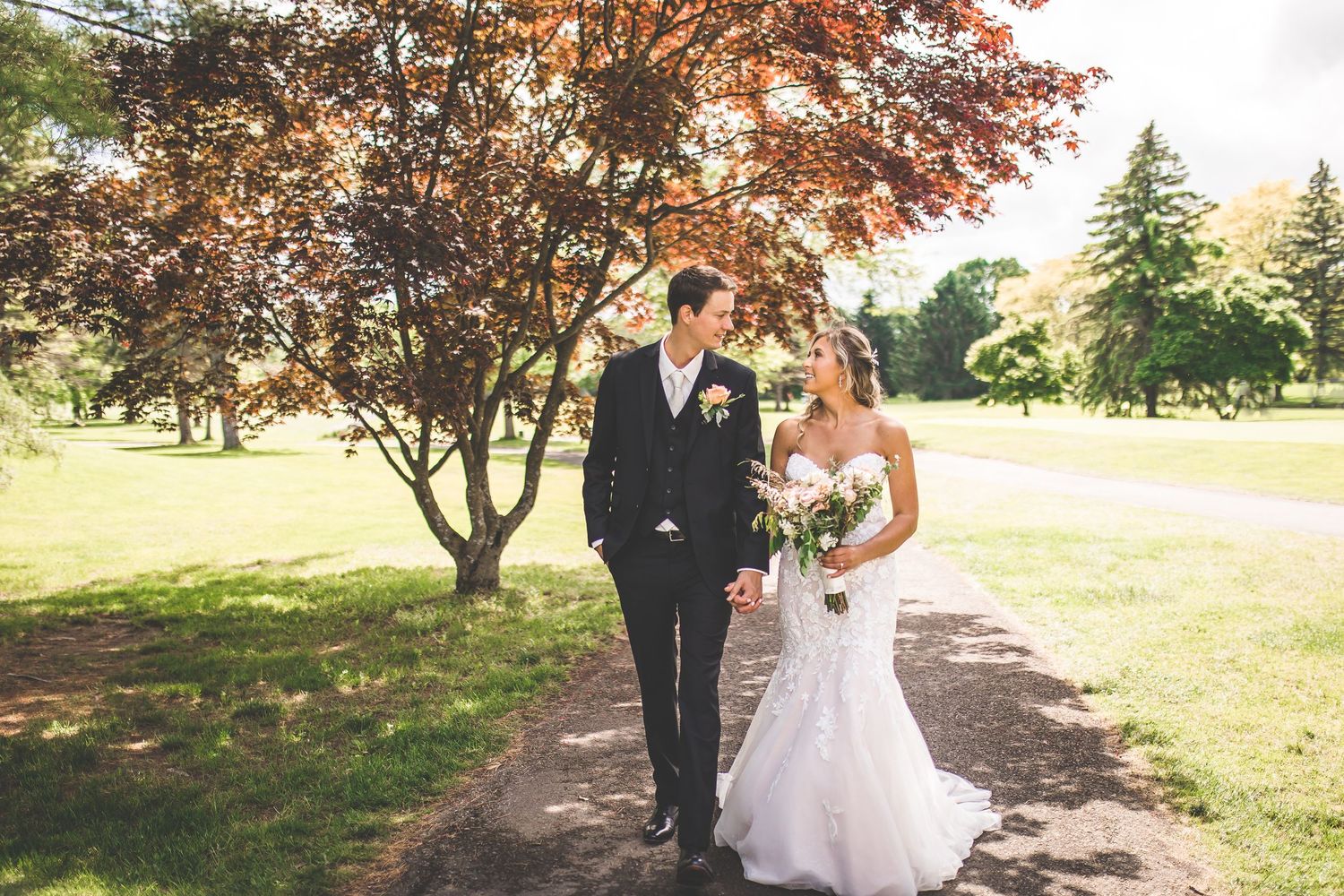 Outdoor wedding photos taken on a tree-lined path during autumn.