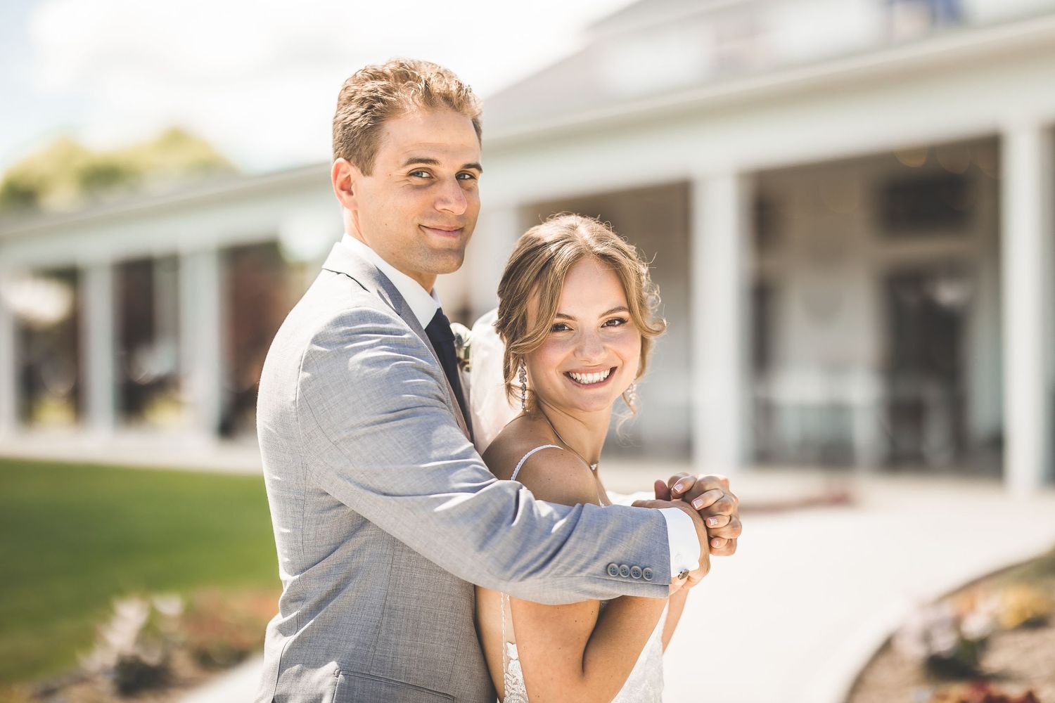 Joyful wedding couple sharing laughter and smiles during outdoor portrait session.
