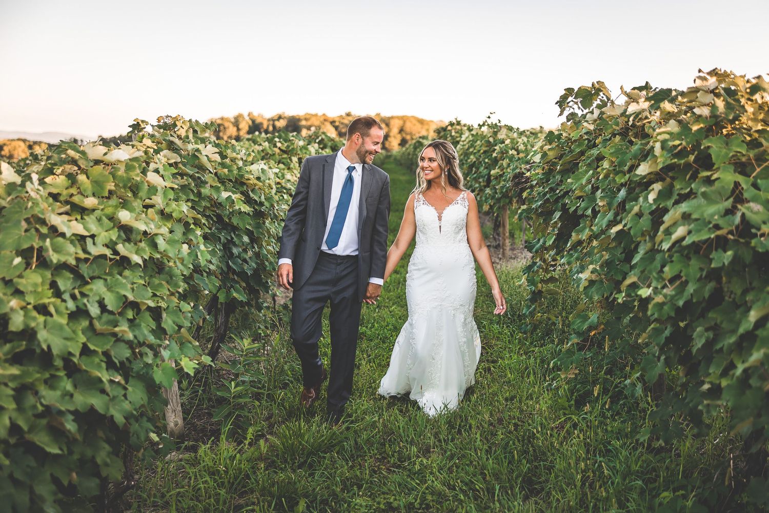 Elegant wedding portrait captured in a scenic vineyard with rolling hills in the background.