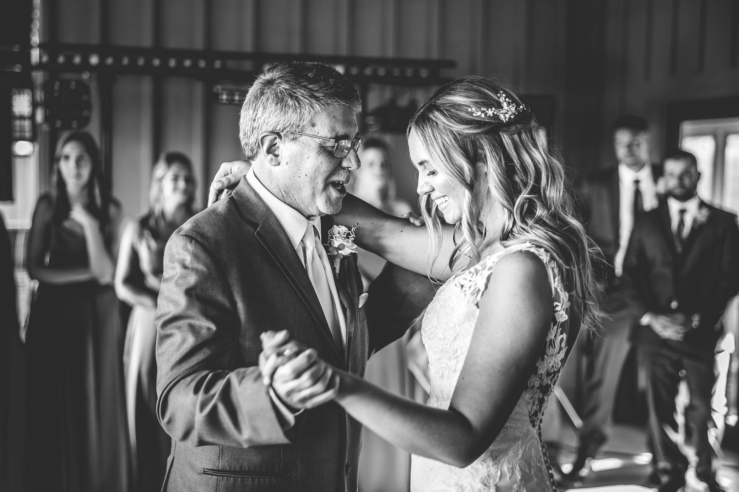 Wedding guests dancing and celebrating on a dimly lit dance floor with string lights overhead.