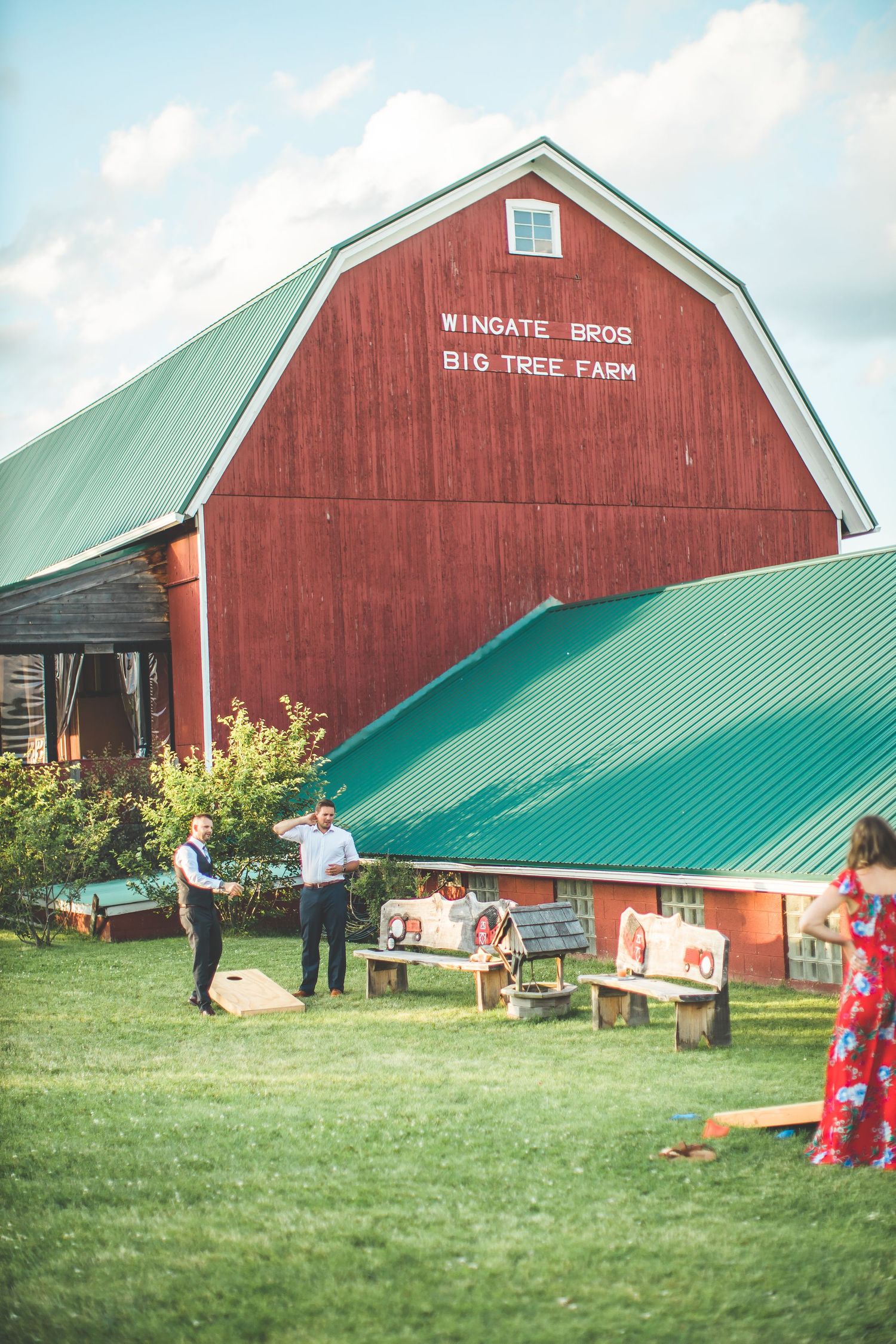 Red barn with green roof at Big Tree Farm shown from multiple angles on a grassy field.
