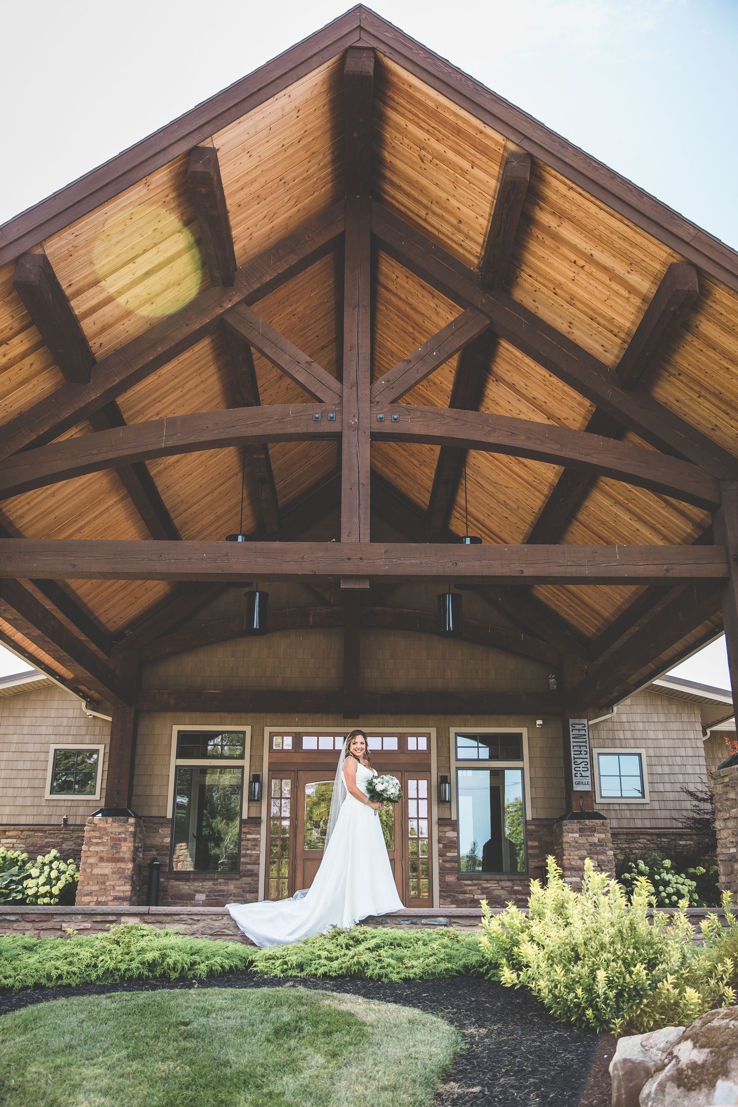 Rustic wooden beam ceiling of a wedding venue with large windows and stone accents.
