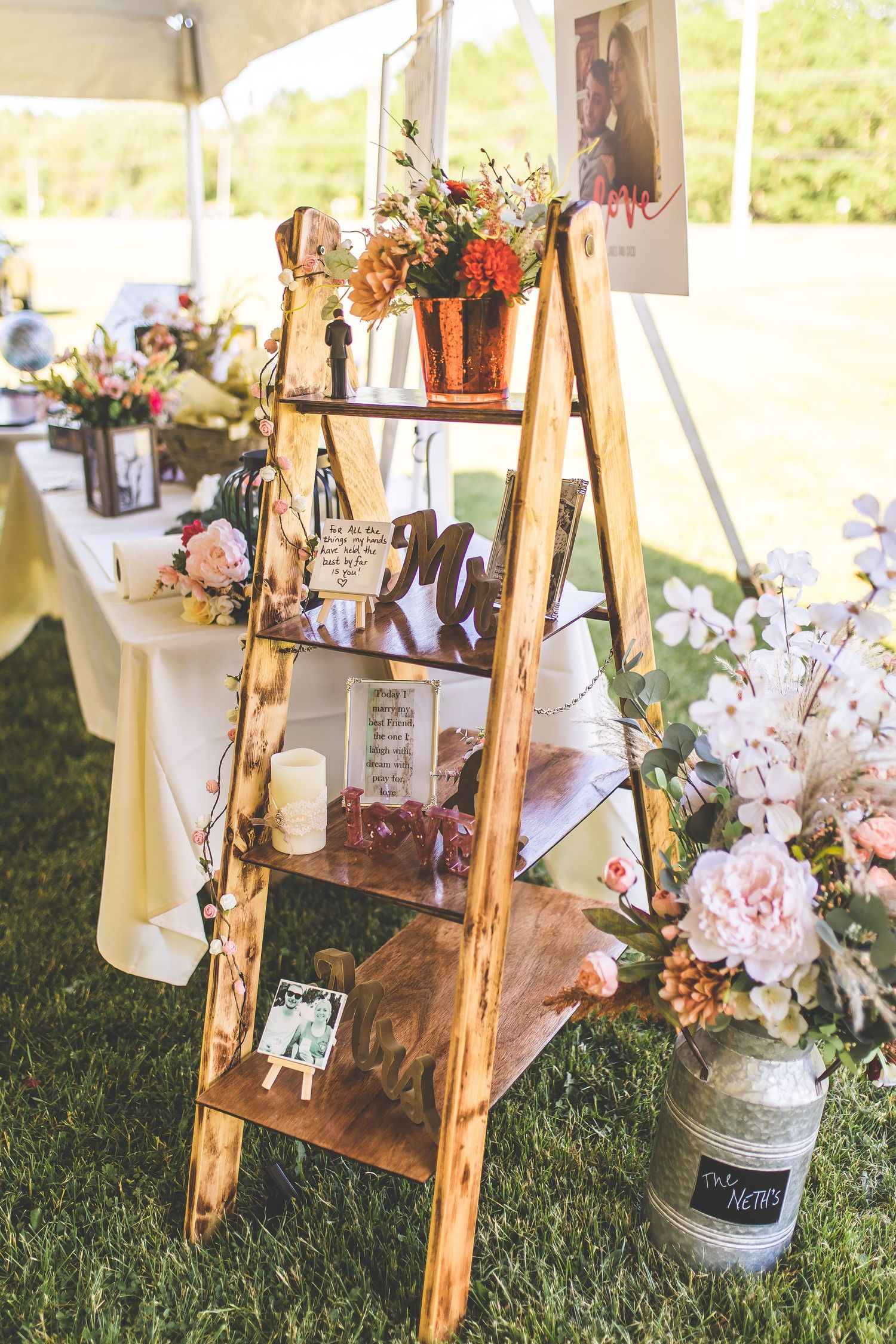 Rustic wooden ladder display with flowers and photos for wedding decor.