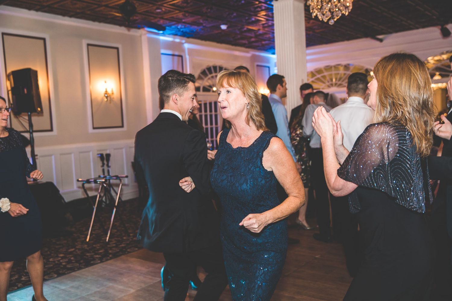 Wedding guests dancing and celebrating on the dance floor under ambient blue lighting.