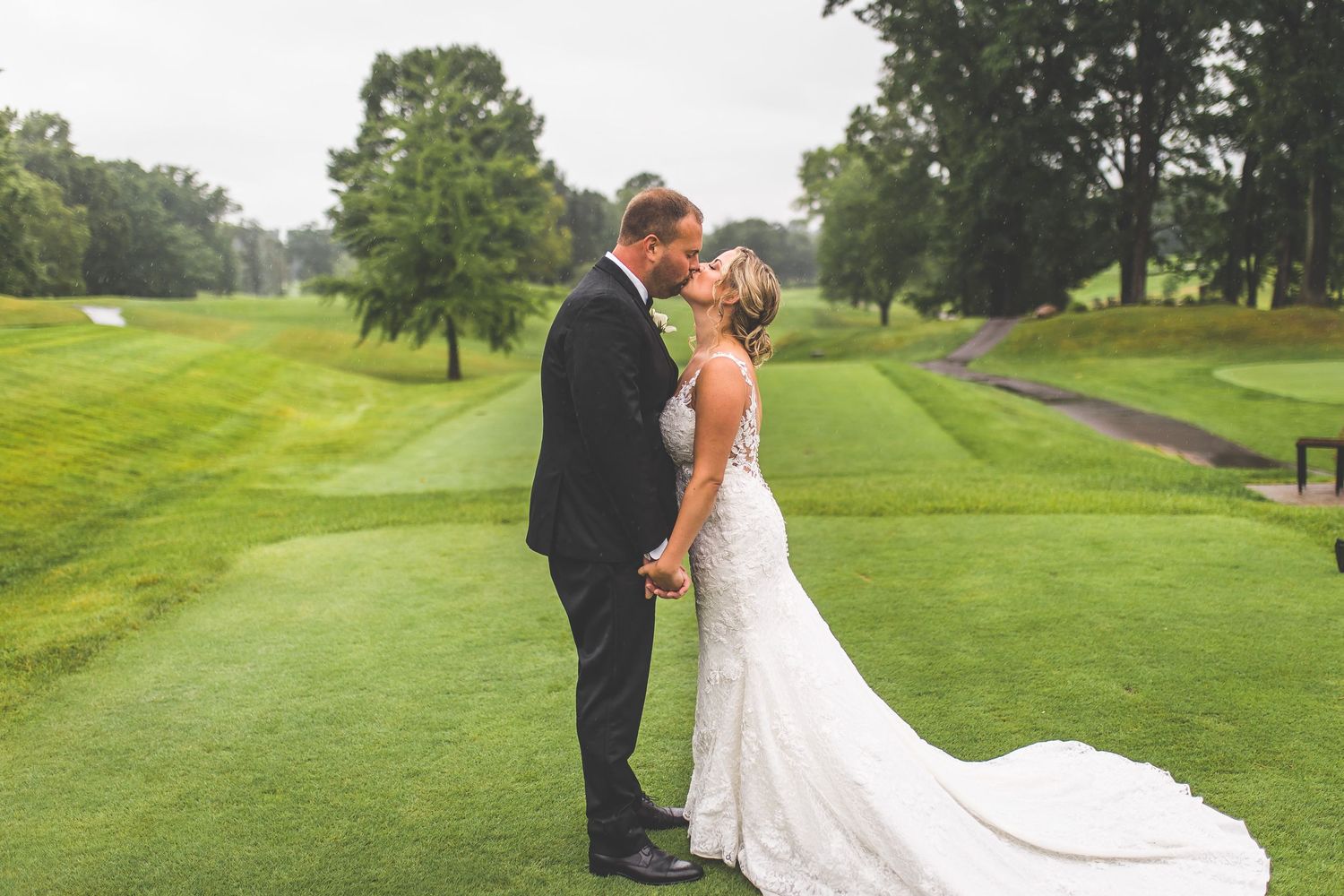Couple embraces while walking along scenic golf course path.
