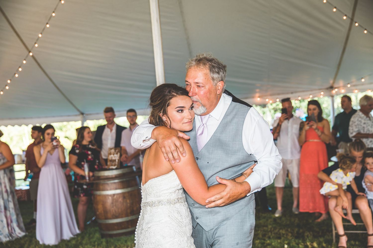 Wedding reception under a white tent with string lights and dancing guests.
