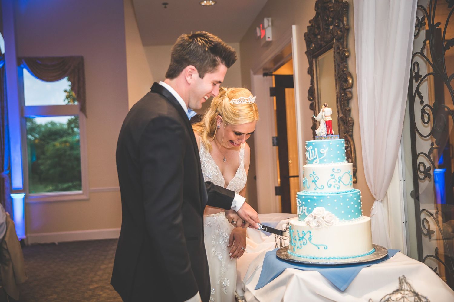 Wedding reception with elegant blue tiered cake and guests celebrating in background.