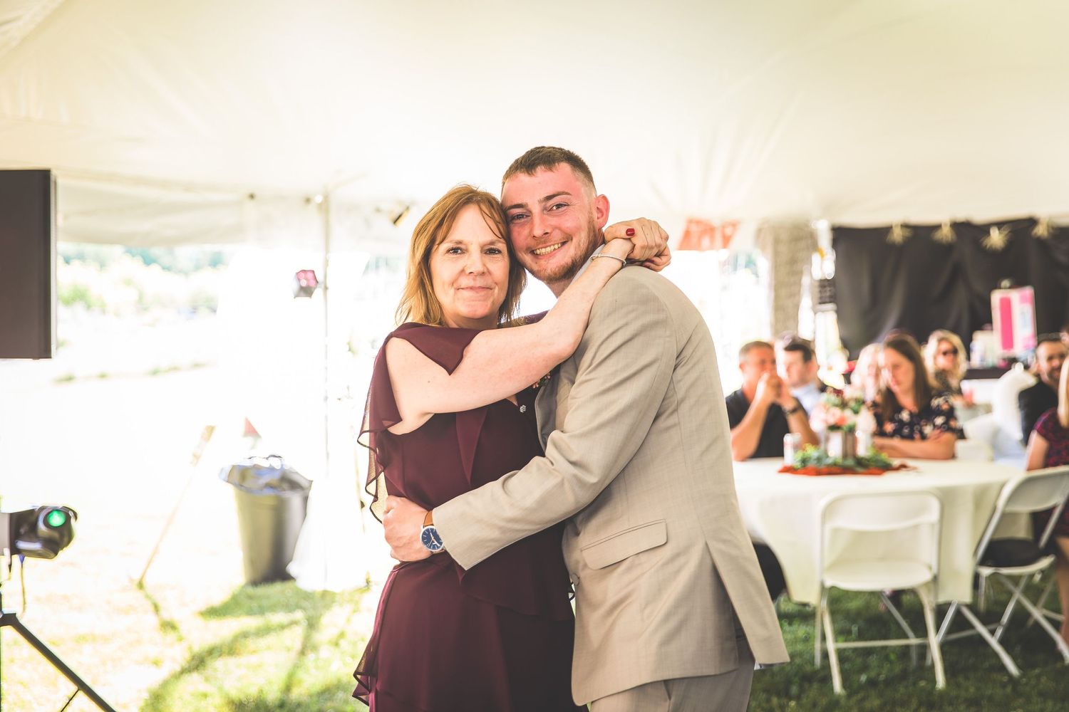 Couple embraces while dancing during emotional moment at outdoor wedding reception.