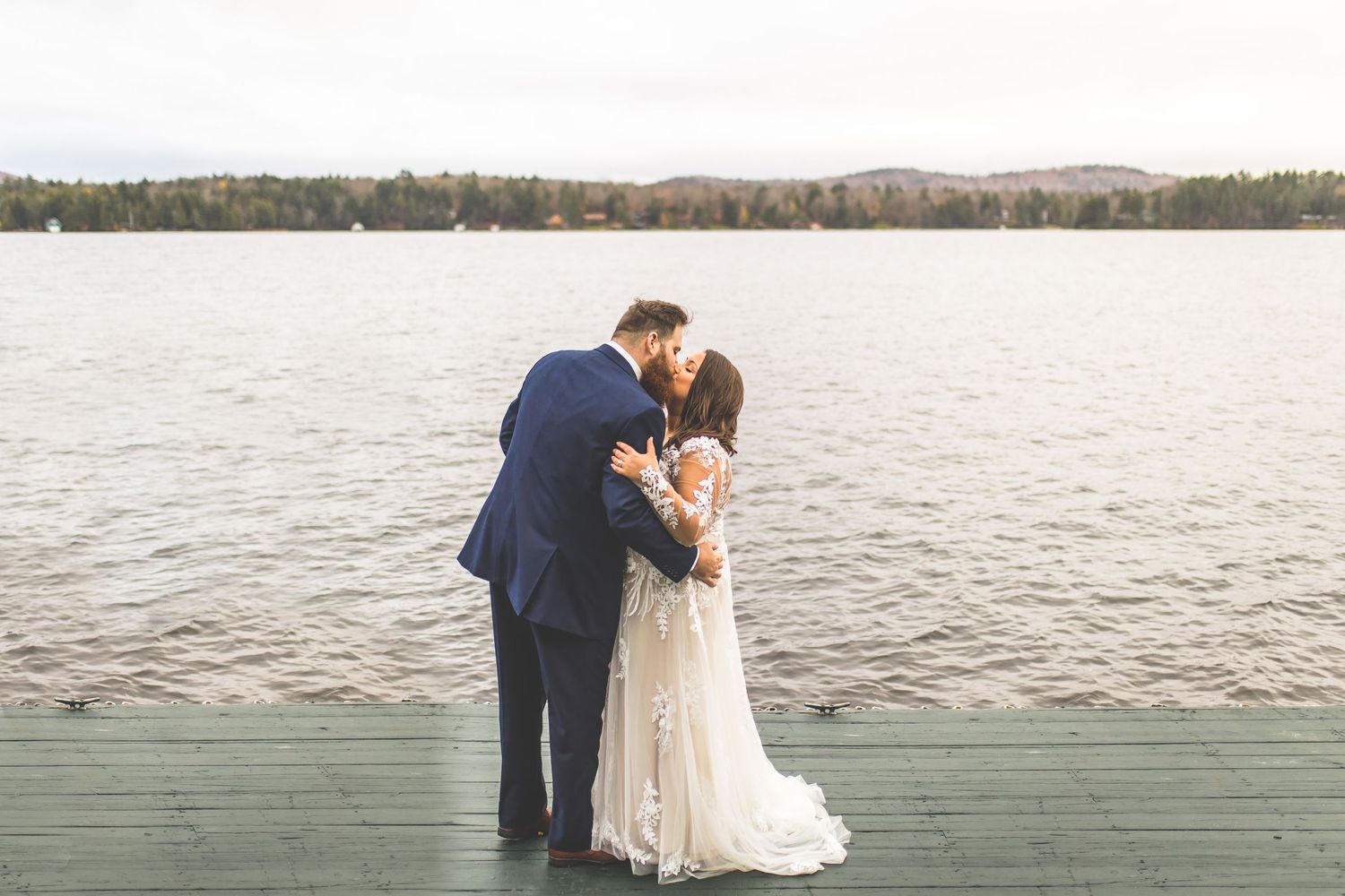 A romantic lakeside wedding photoshoot with mountains and water in the background.