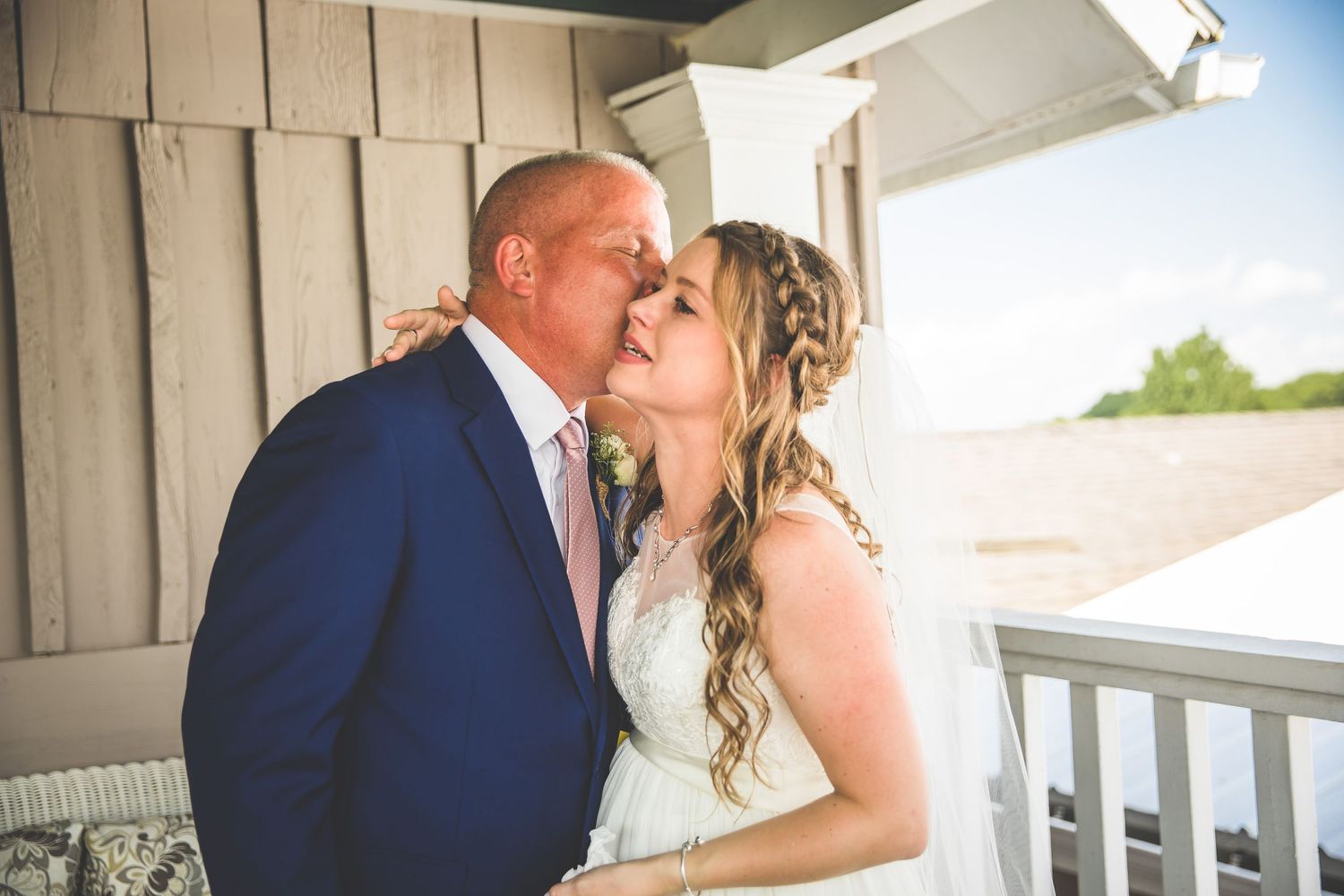 Romantic wedding moment captured on a white porch with elegant decor.