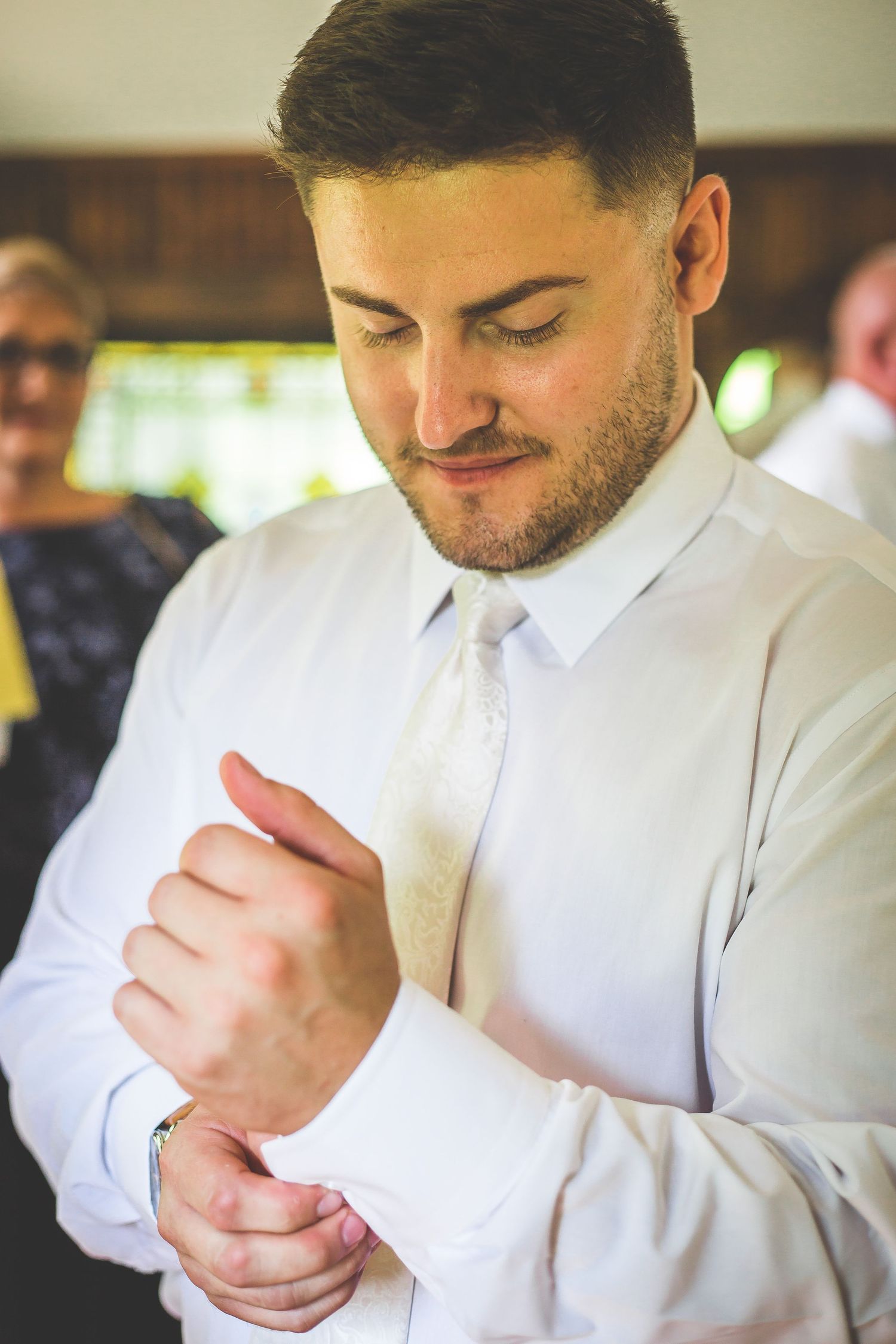 Groom adjusting his white shirt cuff while getting ready for the ceremony.