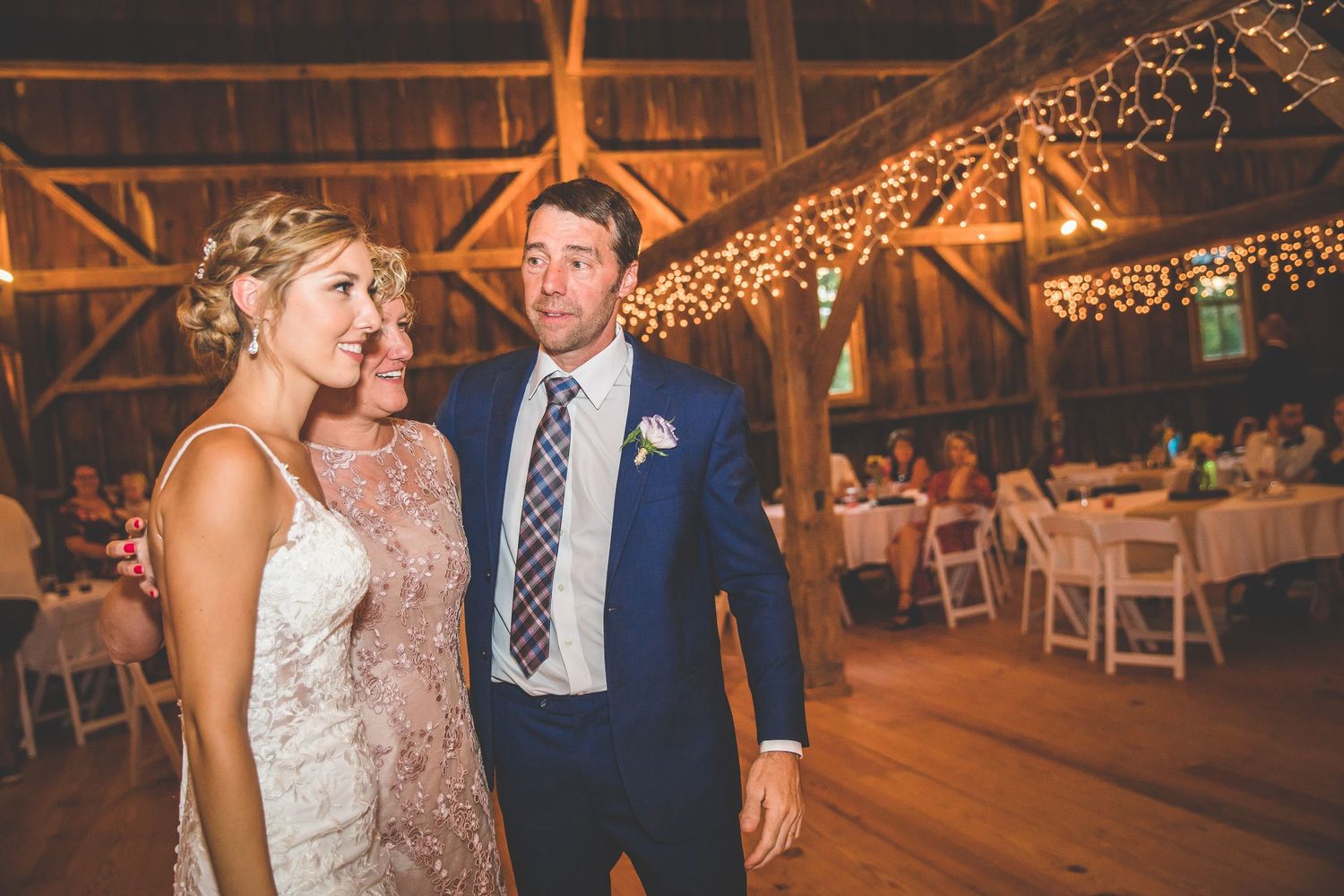 Wedding celebration in a barn decorated with warm string lights.