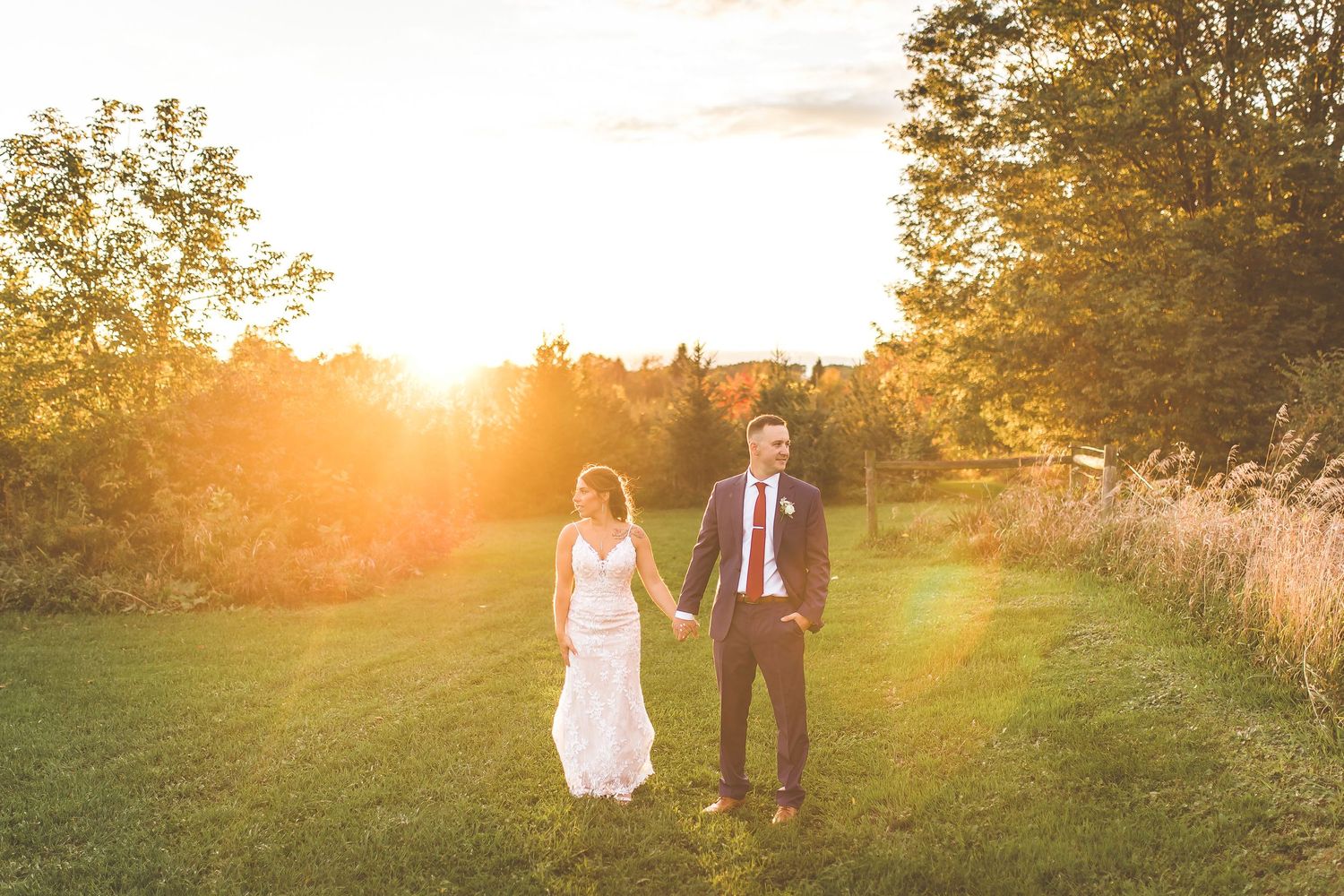 Sunset silhouette of newlyweds standing in a golden field during their wedding portraits.