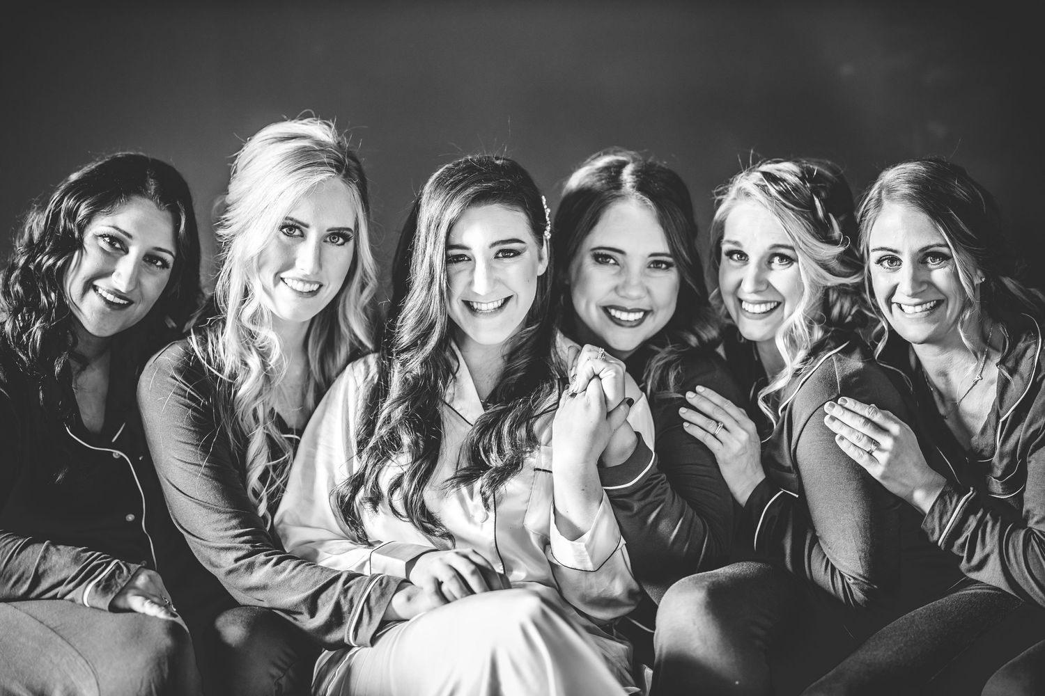 Black and white photo of bridal party members laughing together in a candid moment.