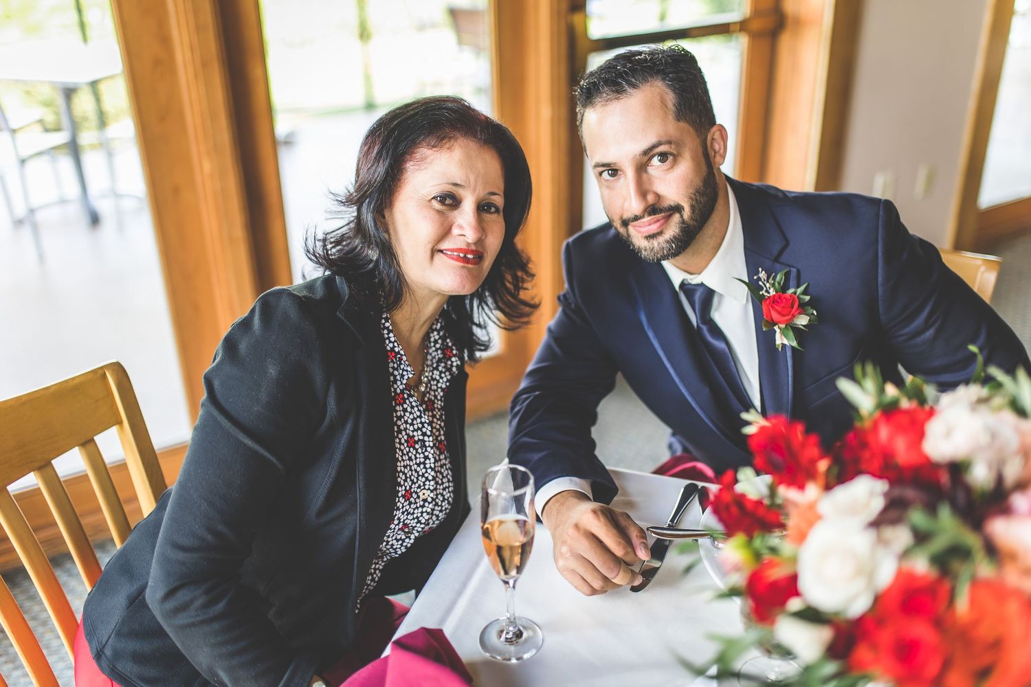 Reception table setting with red floral centerpieces and elegant place settings.