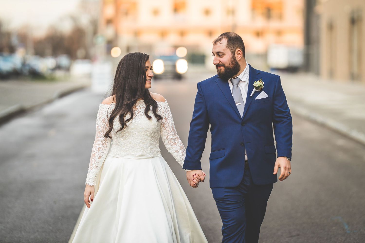 Wedding couple walking hand in hand down a city street.