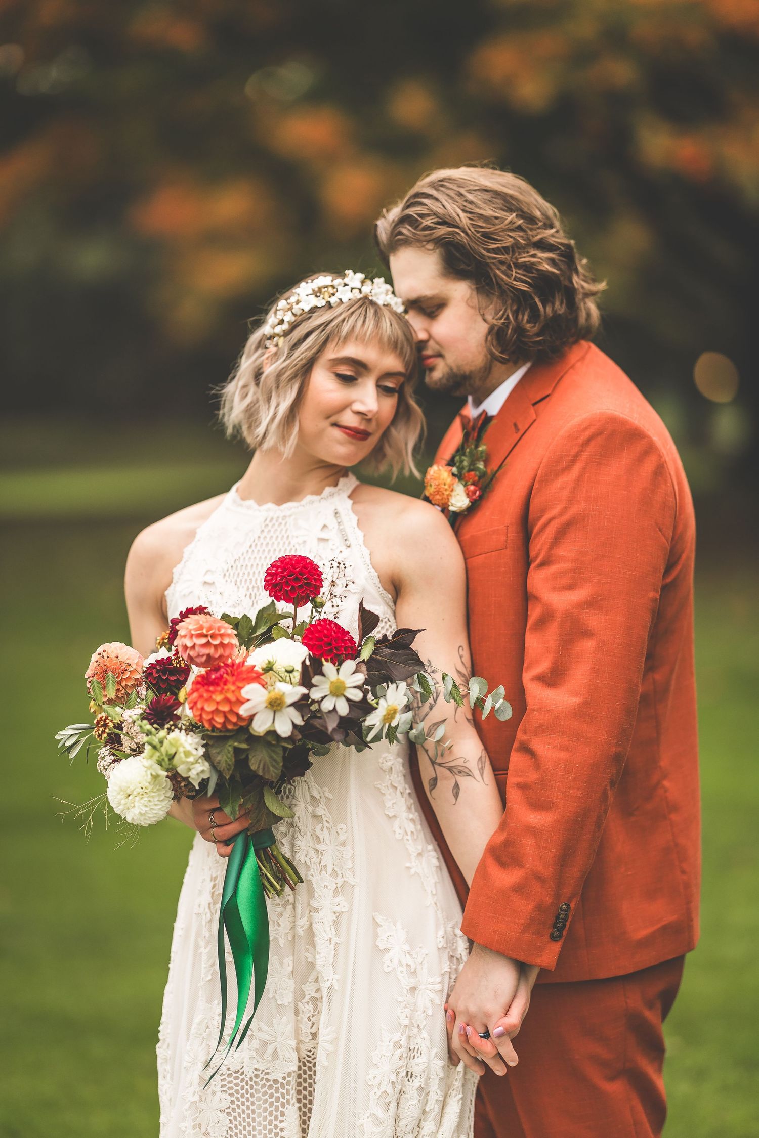 A romantic wedding portrait featuring a colorful bouquet and autumn scenery.