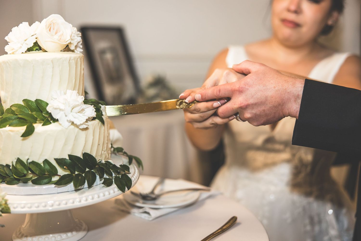 Close-up of wedding cake cutting with white floral decorations.