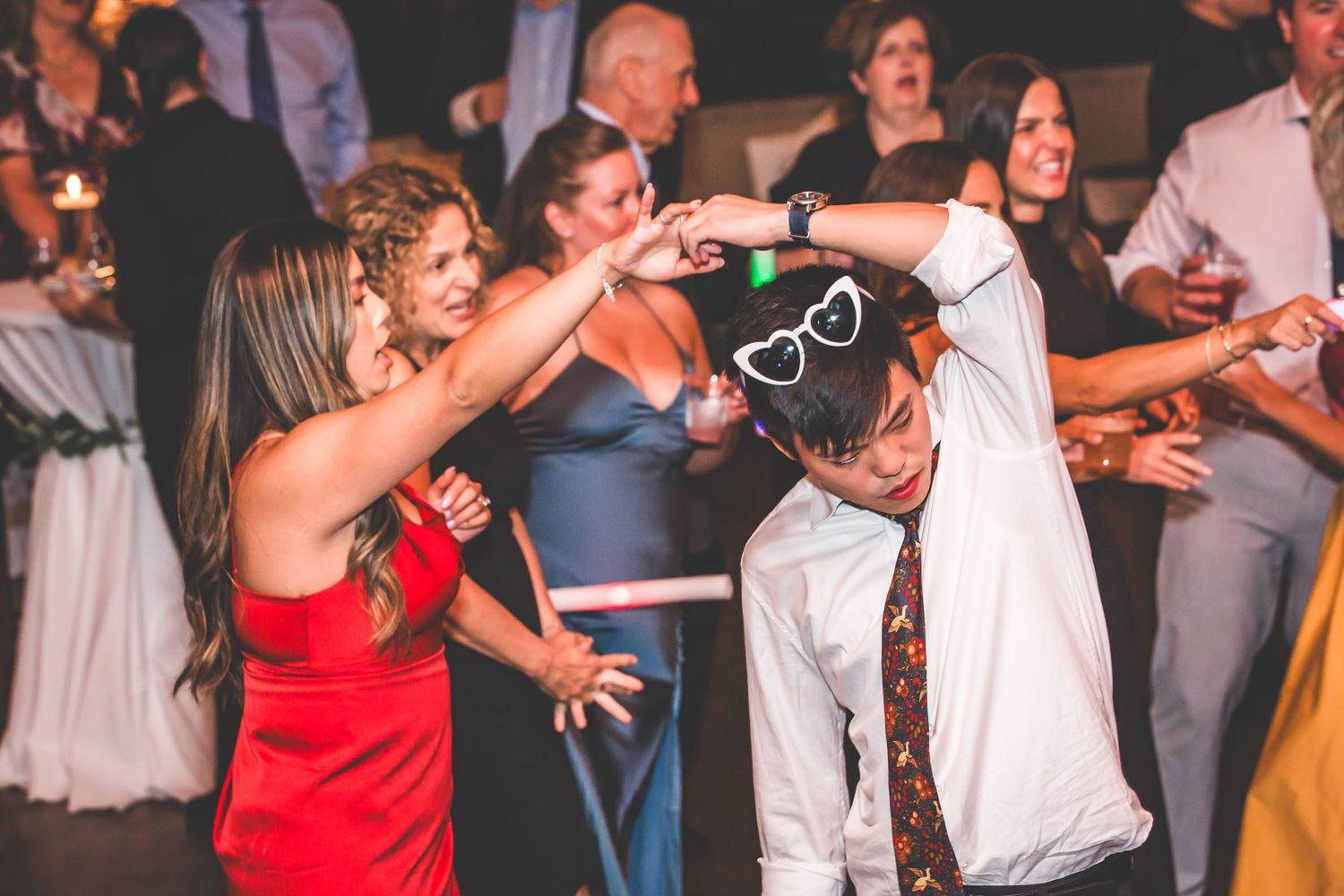 Party guests dancing and having fun with novelty props at wedding reception.