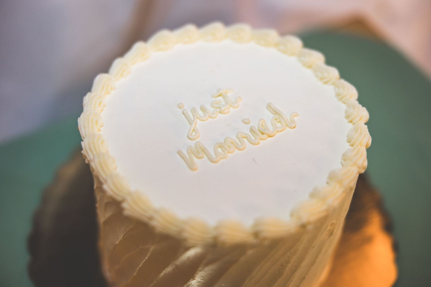 Decorative white frosted cookies with elegant gold lettering displayed at a wedding reception.