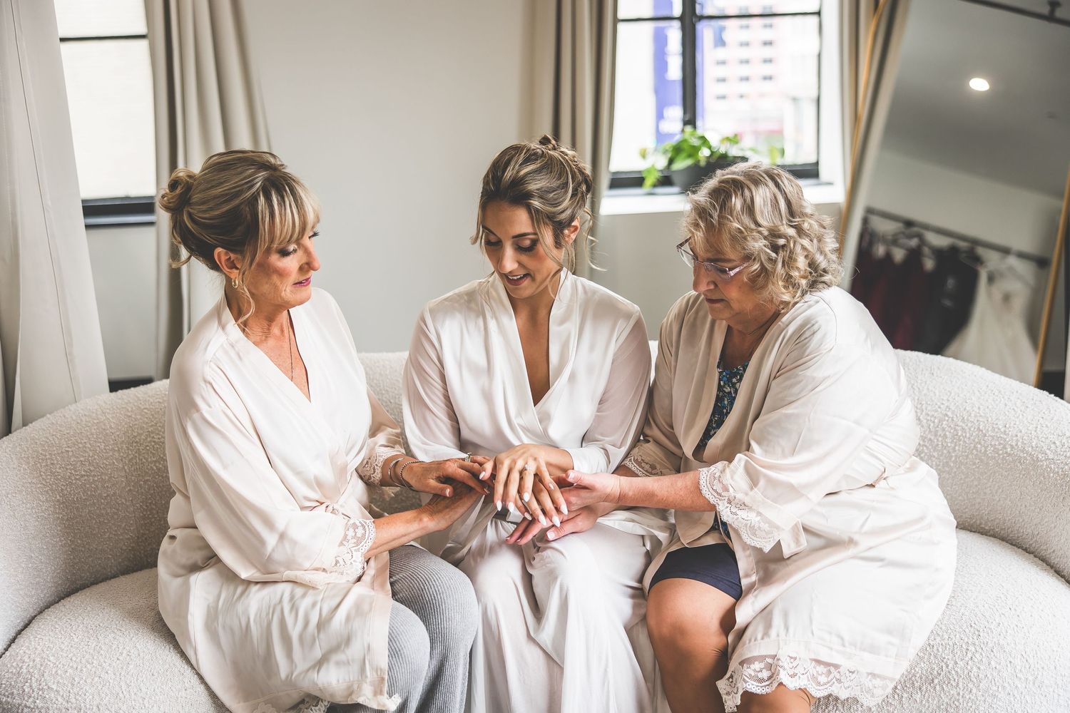 Group gathering on white couch during wedding preparation moments.