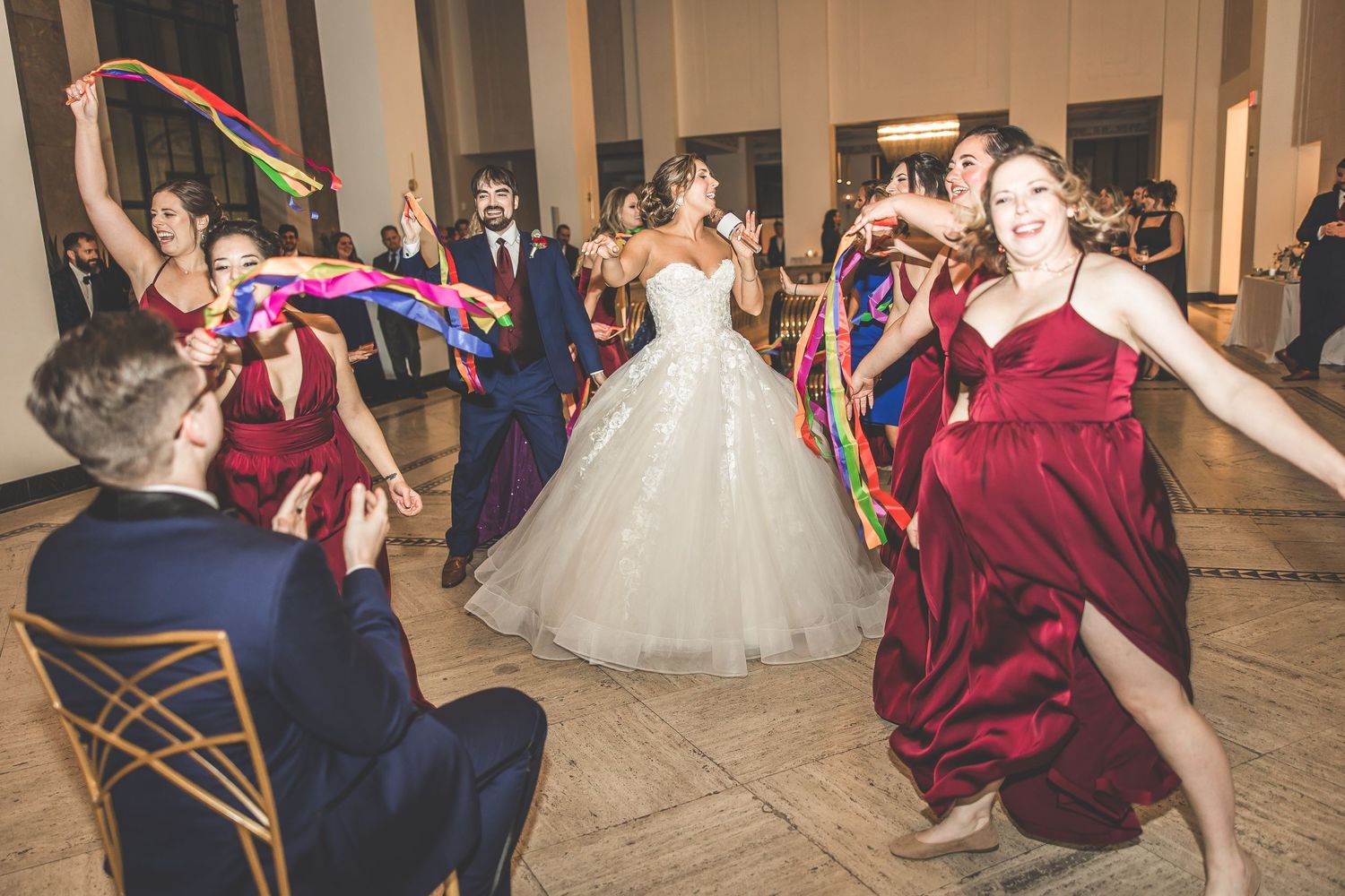 Wedding party dances with colorful ribbons during reception celebration.