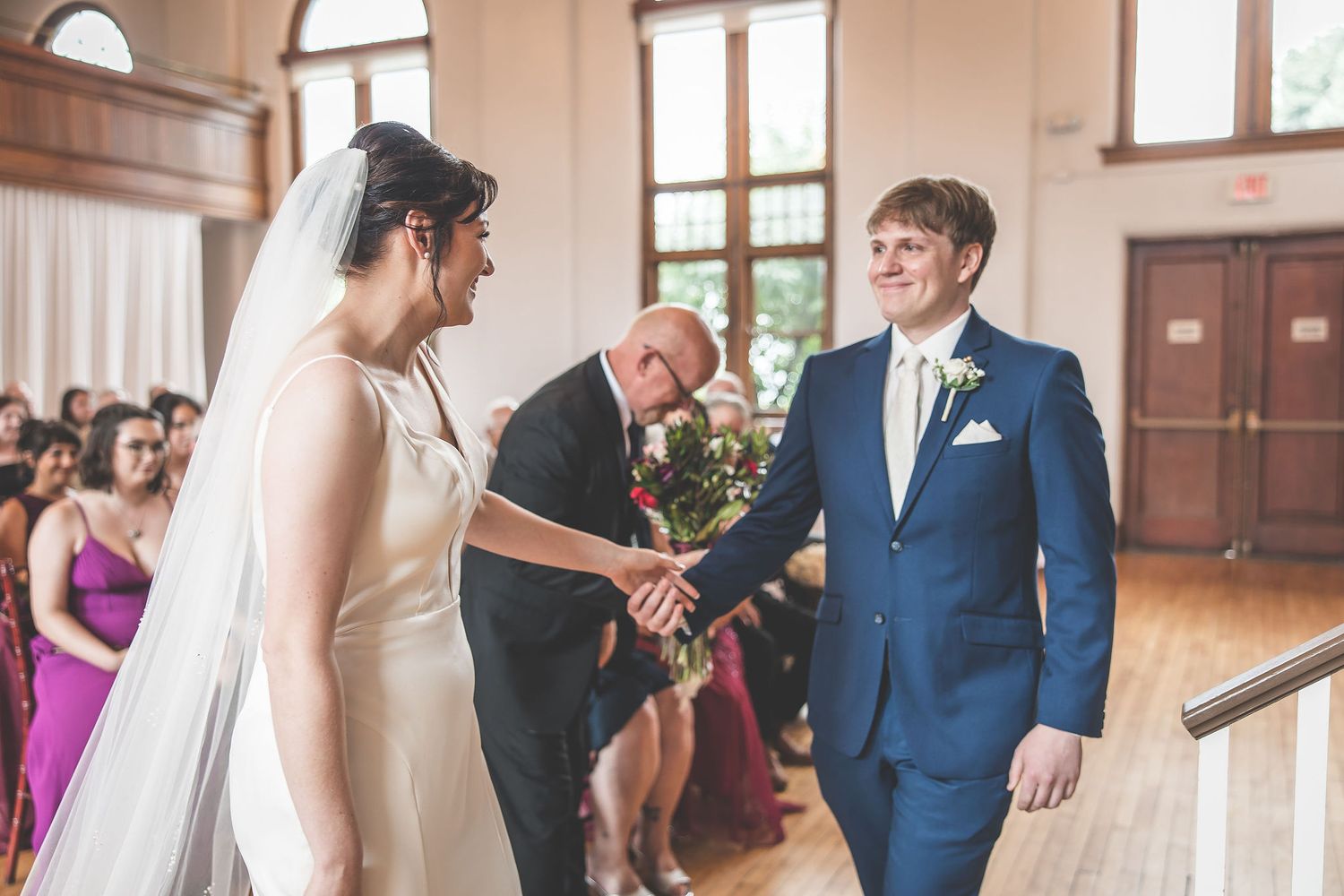 Wedding ceremony taking place in an elegant venue with brick walls and wooden floors.