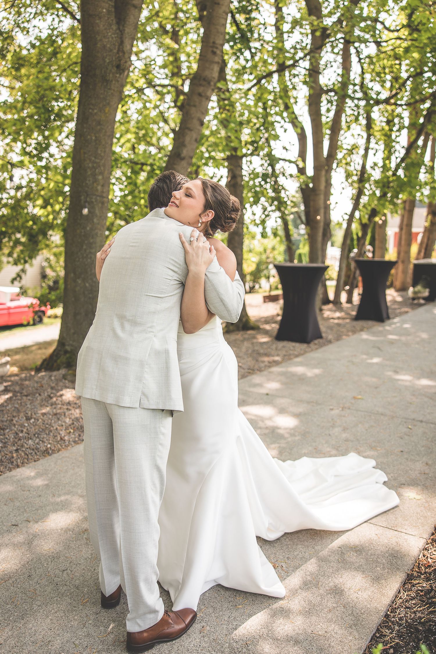 Wedding couple shares tender moments in a garden setting with dappled sunlight and trees.