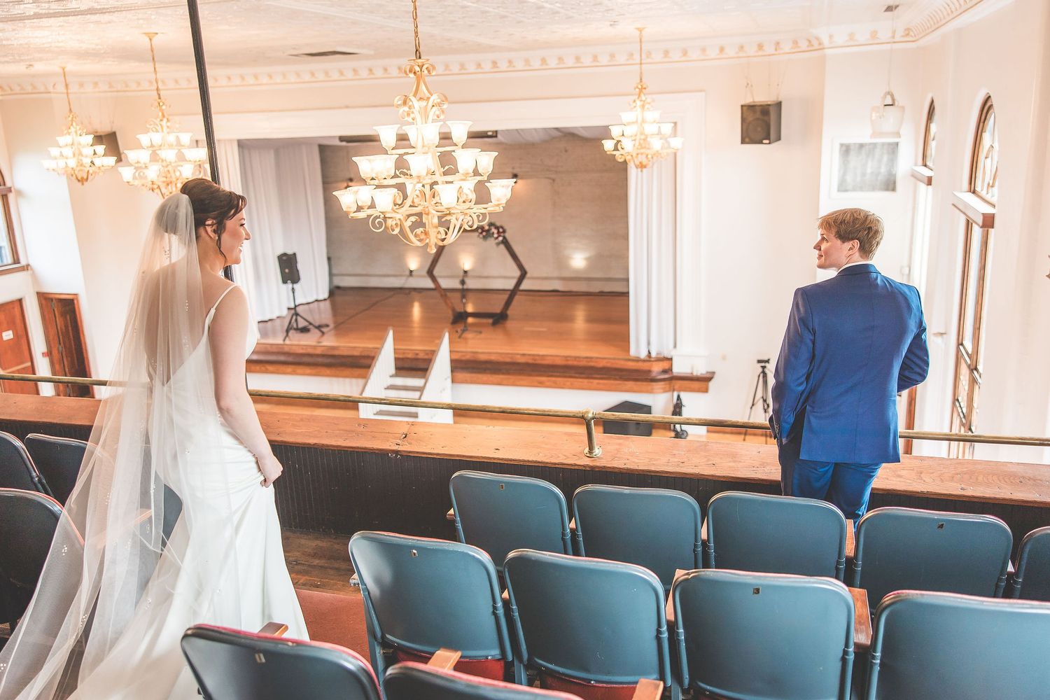 Wedding ceremony space with elegant chandeliers and rows of teal chairs.
