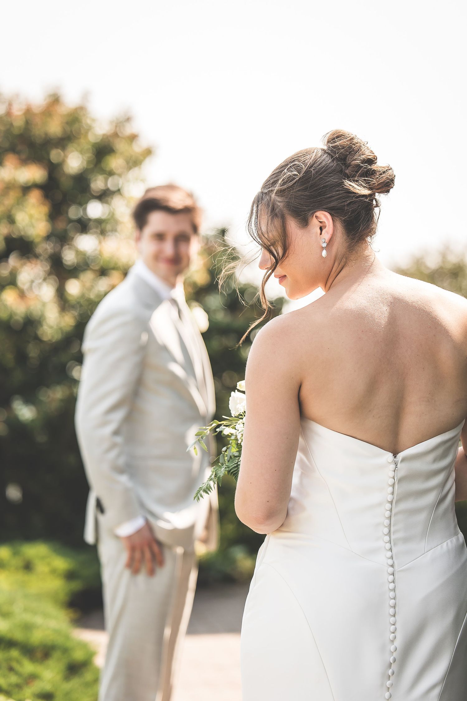 Close-up details of a strapless wedding dress with button details in golden sunlight.