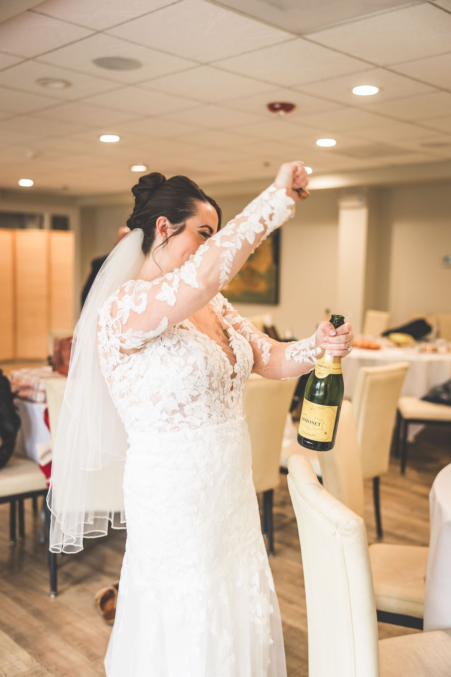 Bride and bridesmaids celebrate with champagne in getting-ready room.