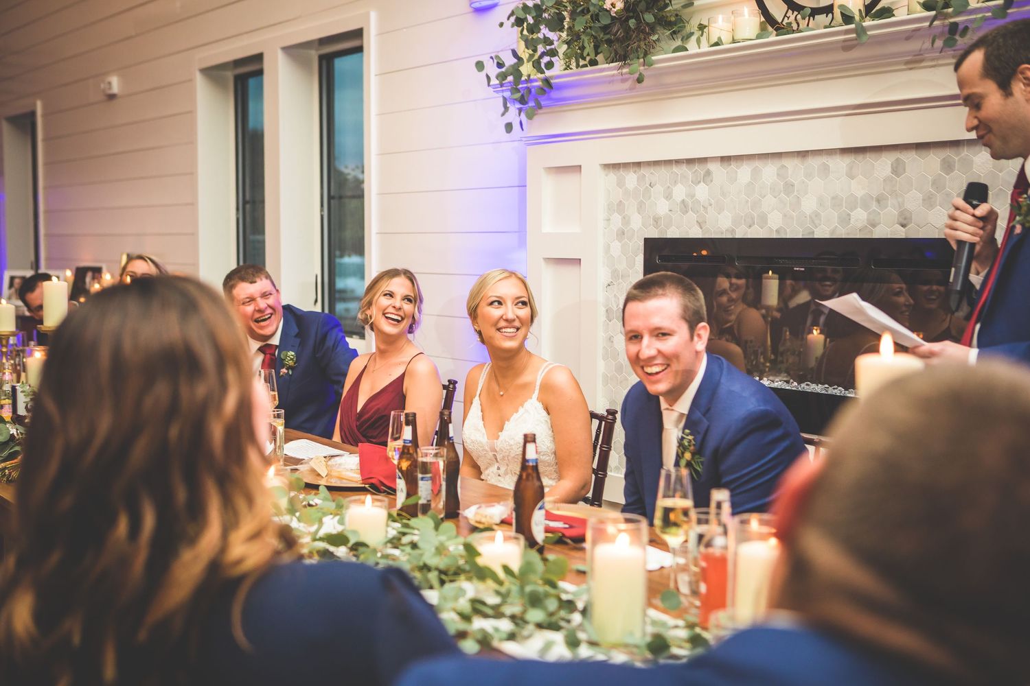 Wedding guests enjoying conversation at an elegant reception dinner with fireplace backdrop.