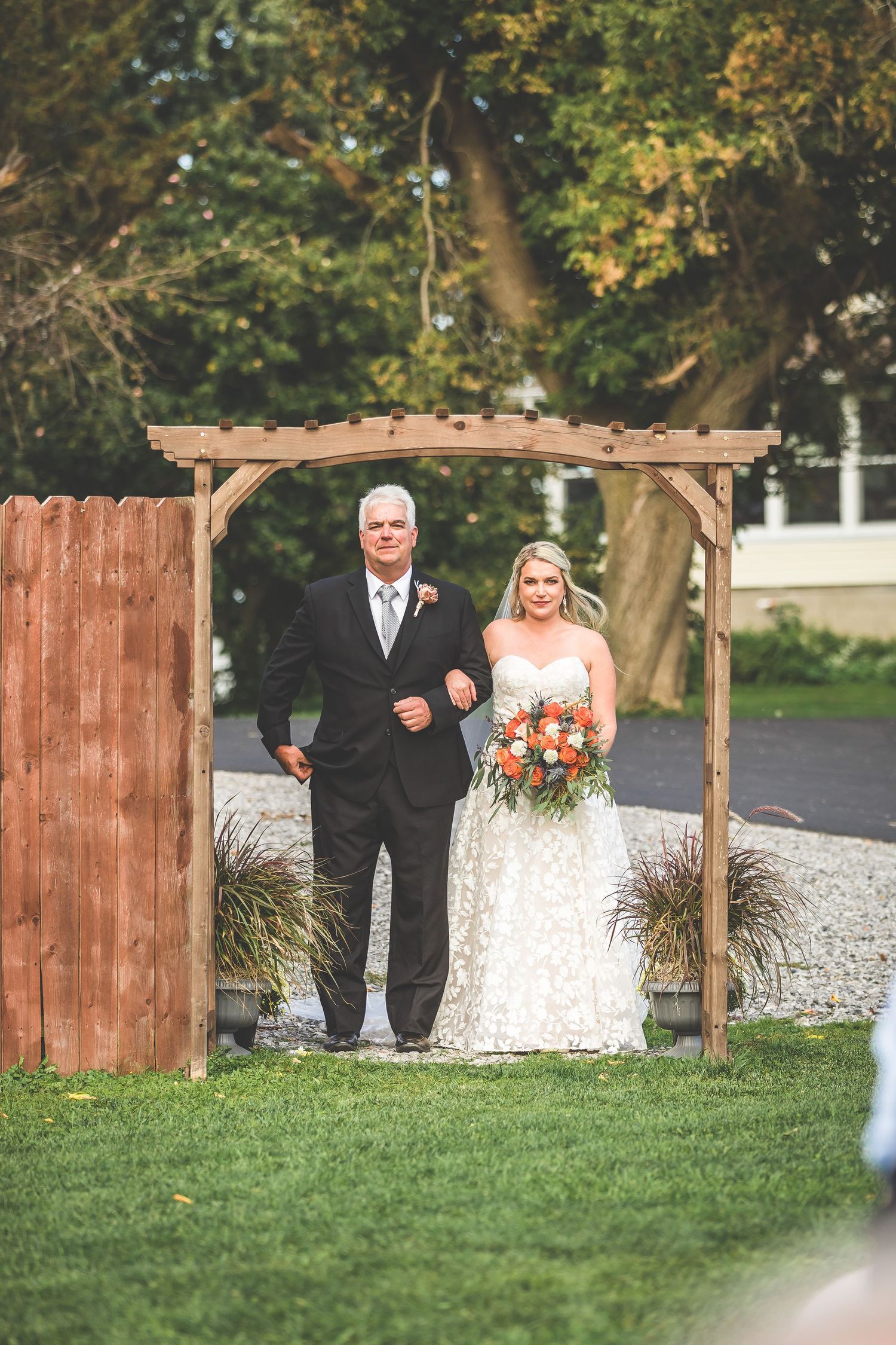 Wedding ceremony entrance with wooden arch and couple walking through.