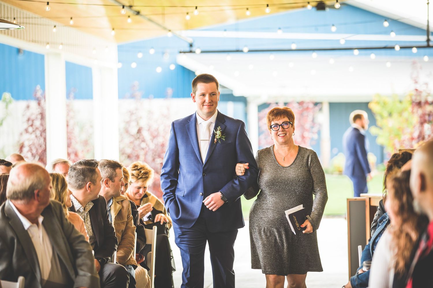 Wedding guests mingle in a bright indoor-outdoor venue space.