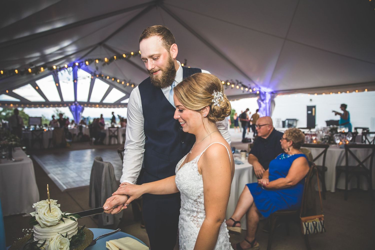 Wedding reception dance party under a white tent with string lights.