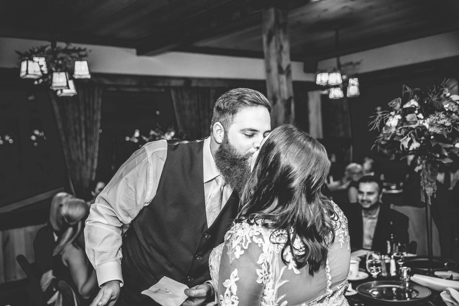Black and white photo captures intimate moment between couple during wedding reception.