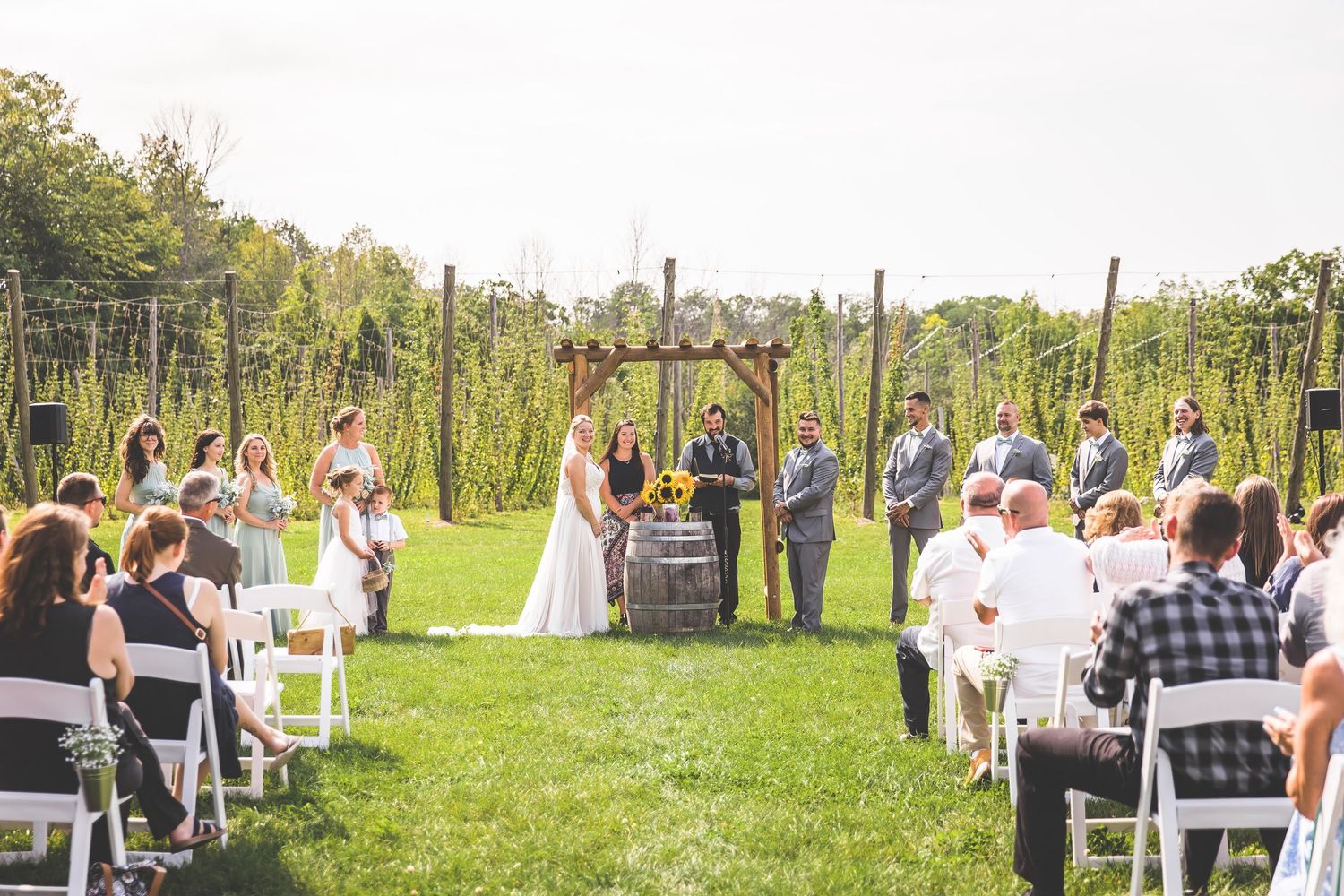 Panoramic shot of wedding ceremony seating arrangement in a rustic outdoor setting.