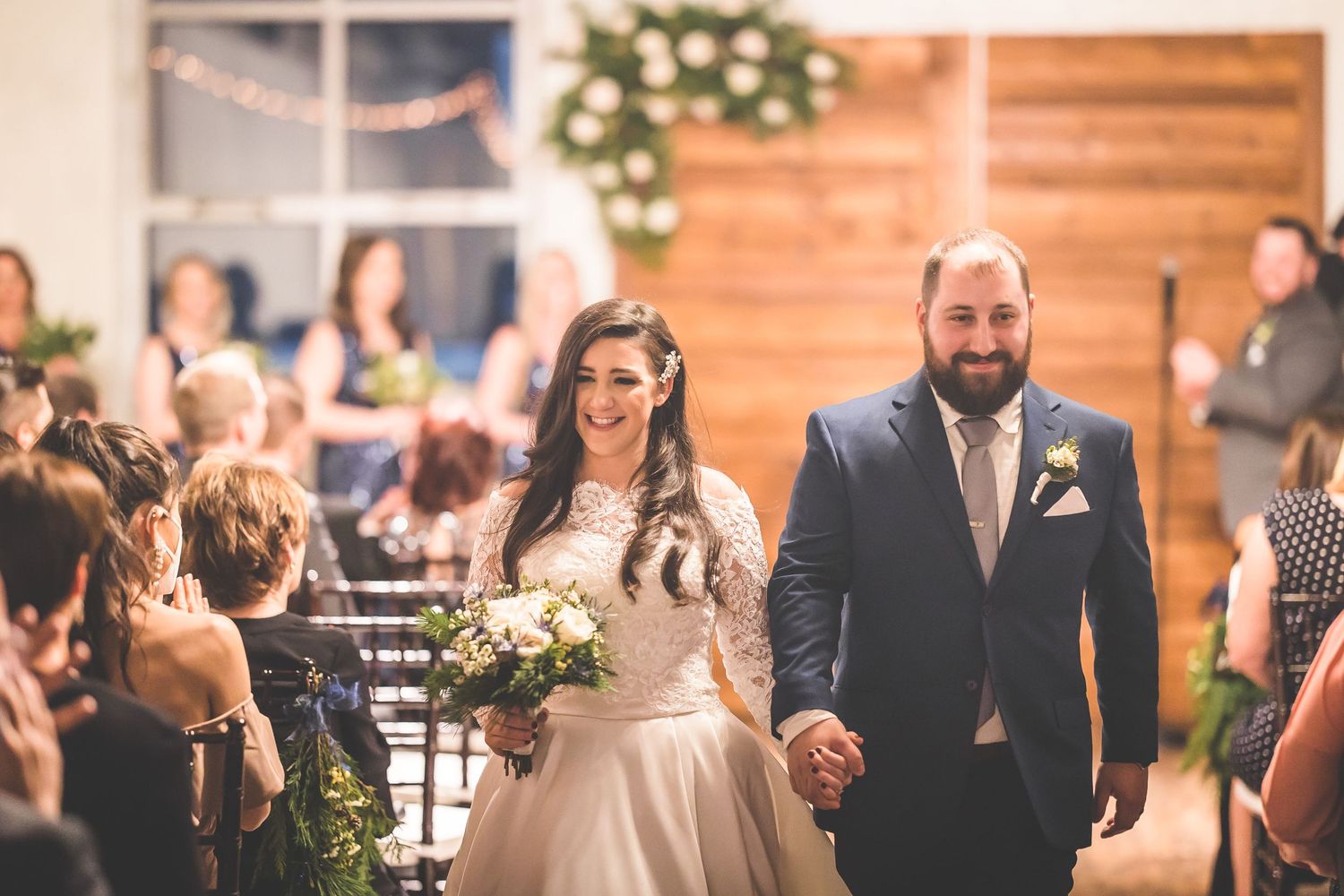 Wedding reception venue decorated with floral arrangements and wooden accent walls.