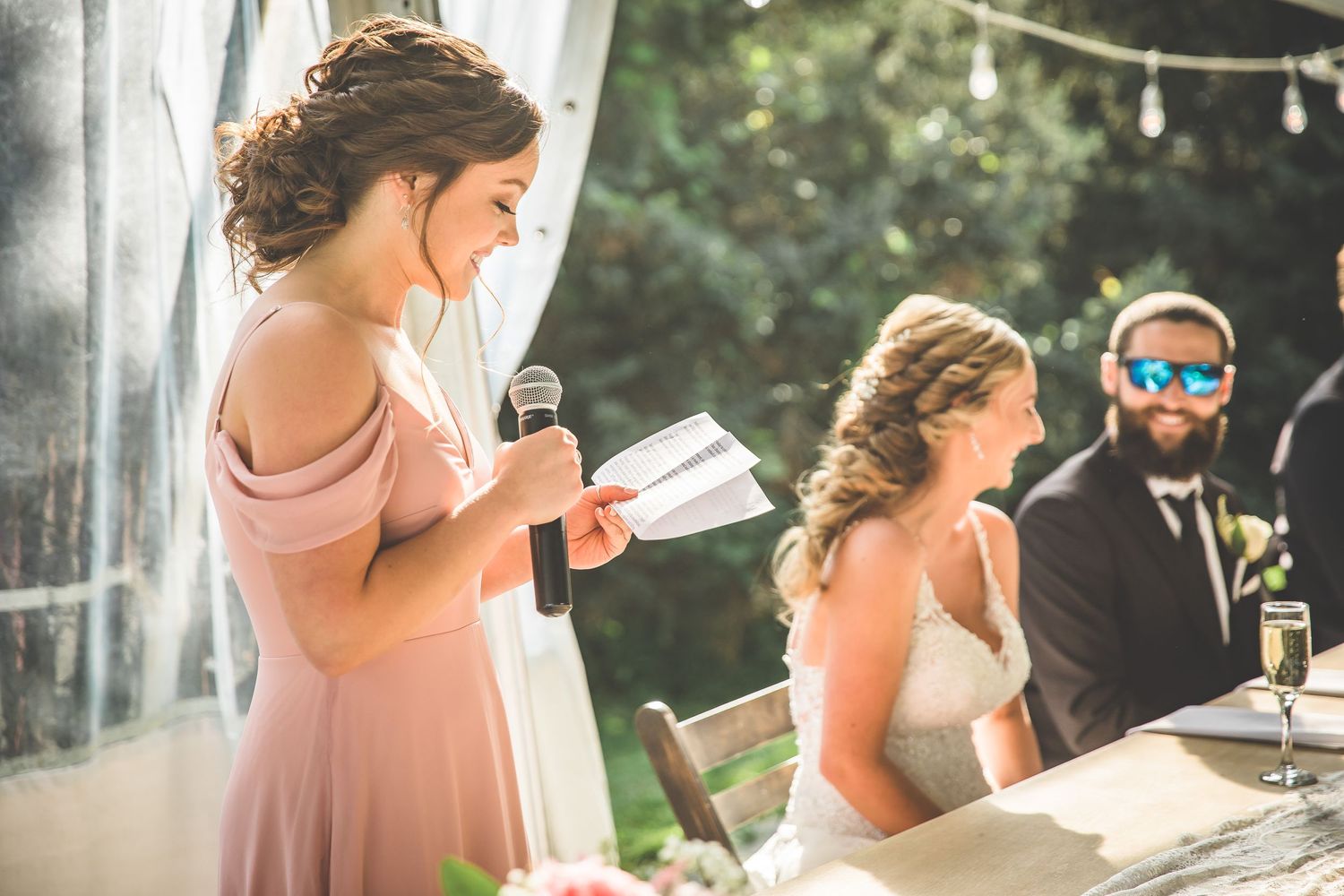 Wedding guests raise glasses during emotional toasts at outdoor reception.