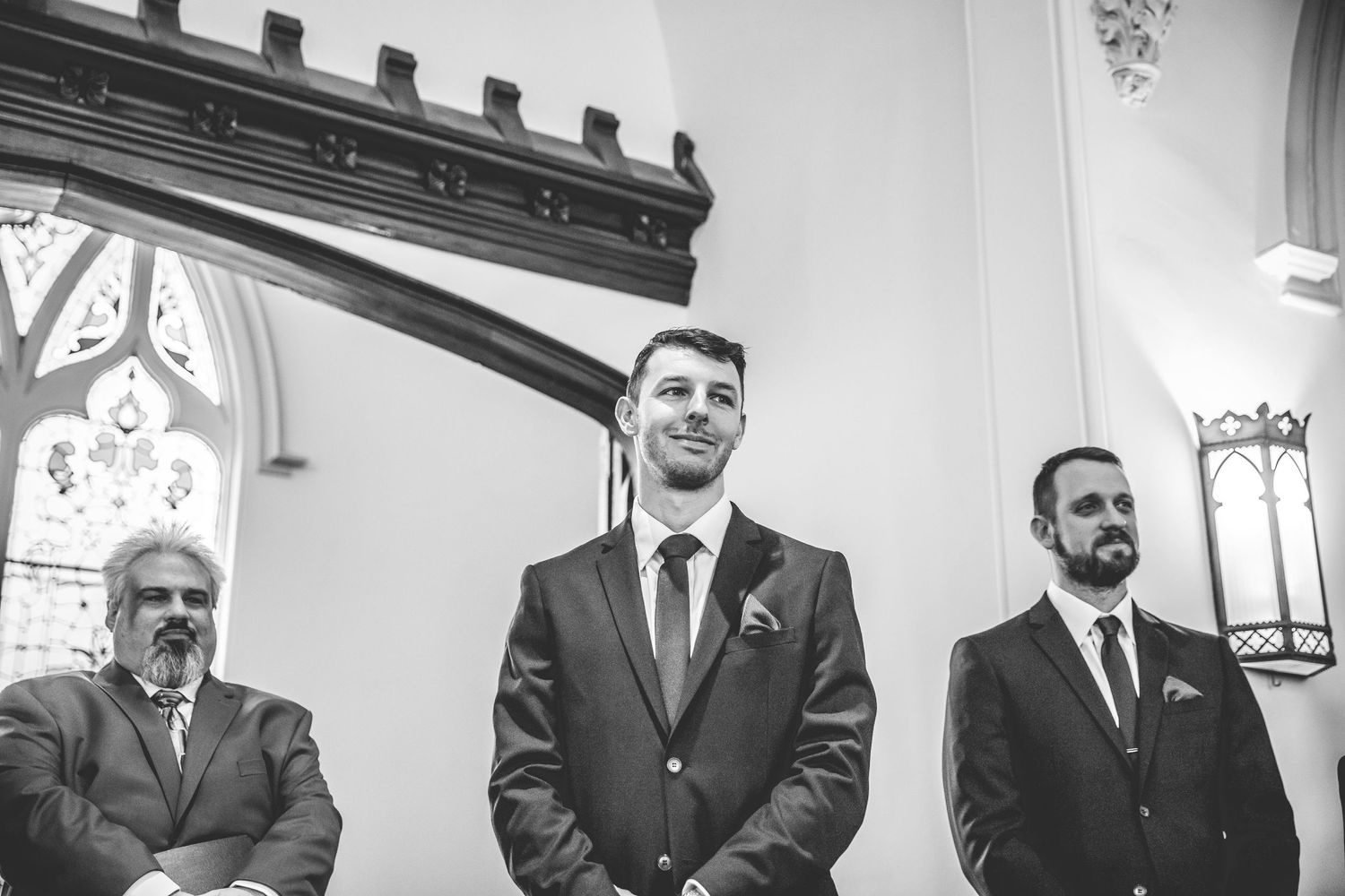 Black and white photo of wedding attendees in formal attire inside a church.