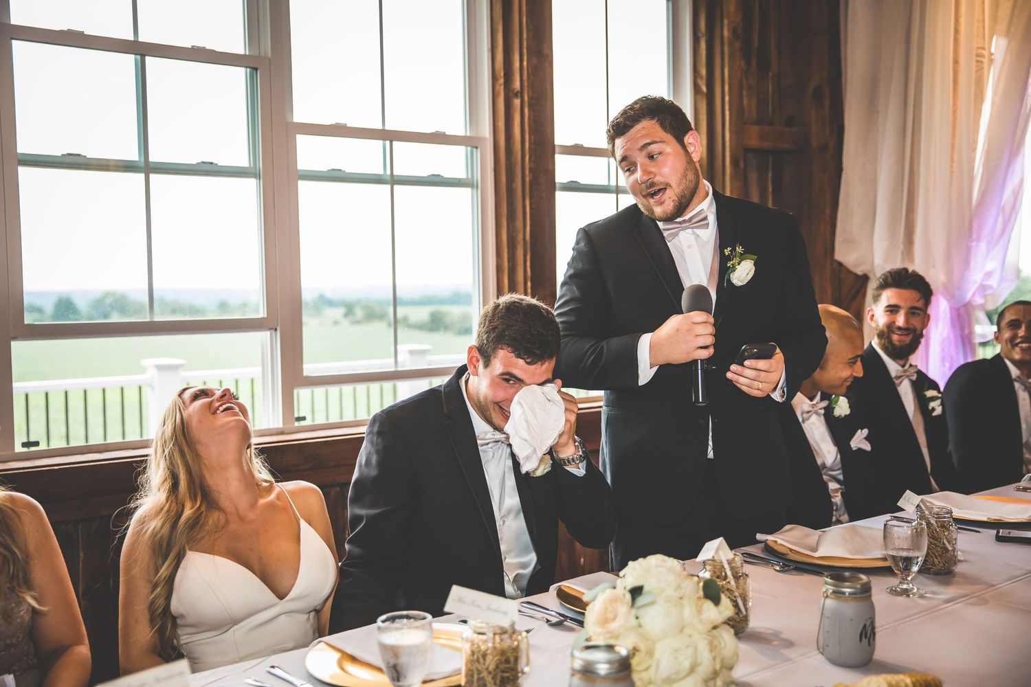 Wedding reception speech brings laughter to head table during celebration.