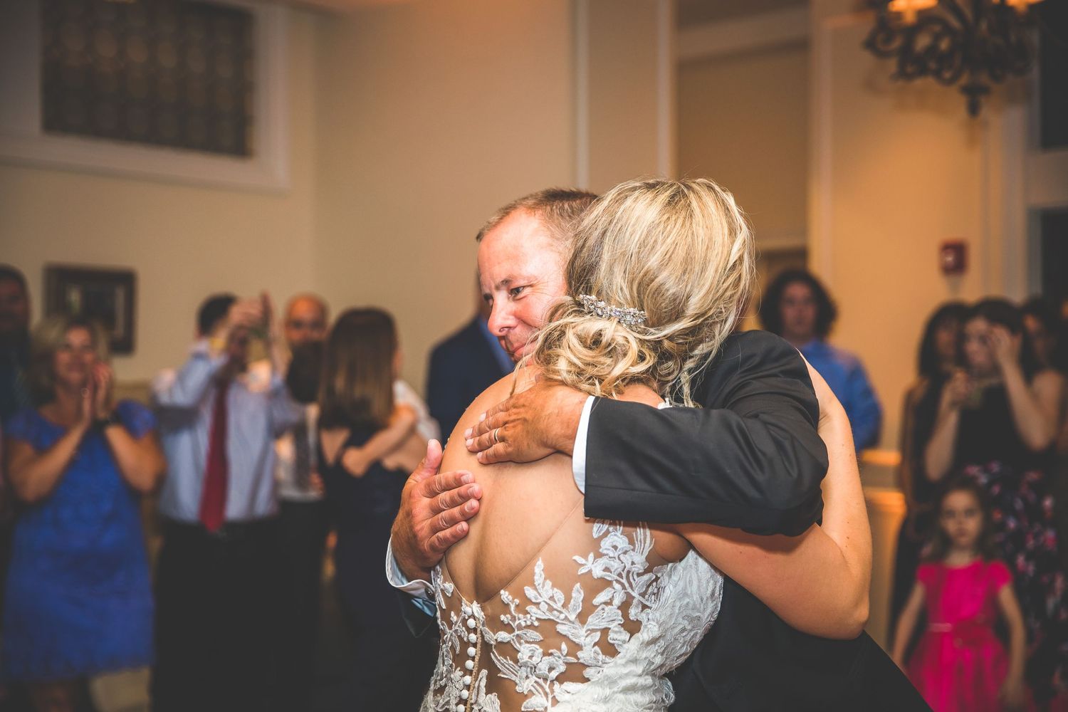 Wedding reception dance floor filled with guests celebrating under warm lighting.