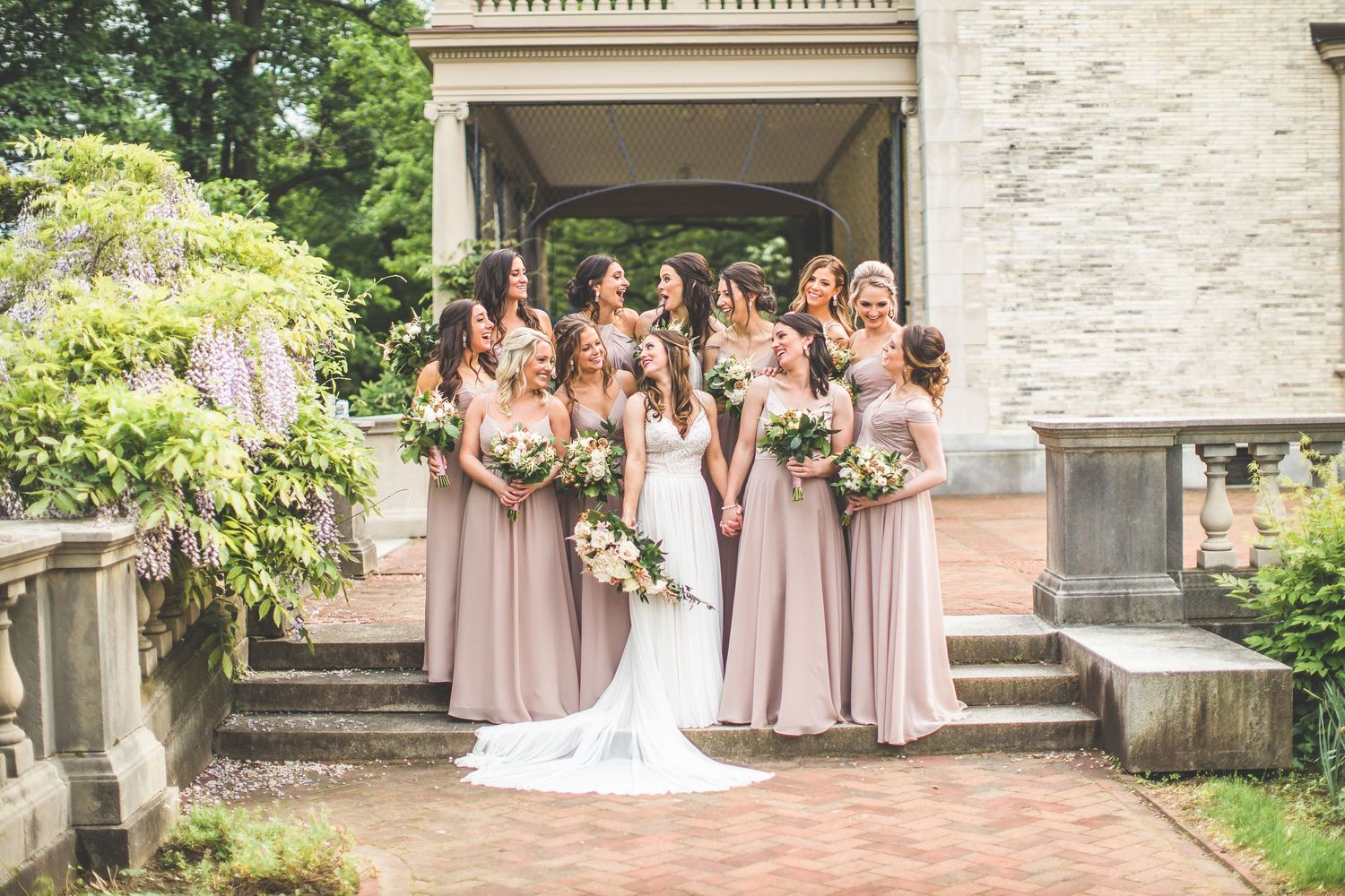 Wedding party posing on stone steps of an elegant building with classic architecture.