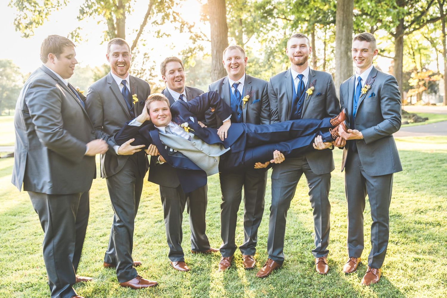 Groomsmen in navy suits show off colorful socks in fun group photo.