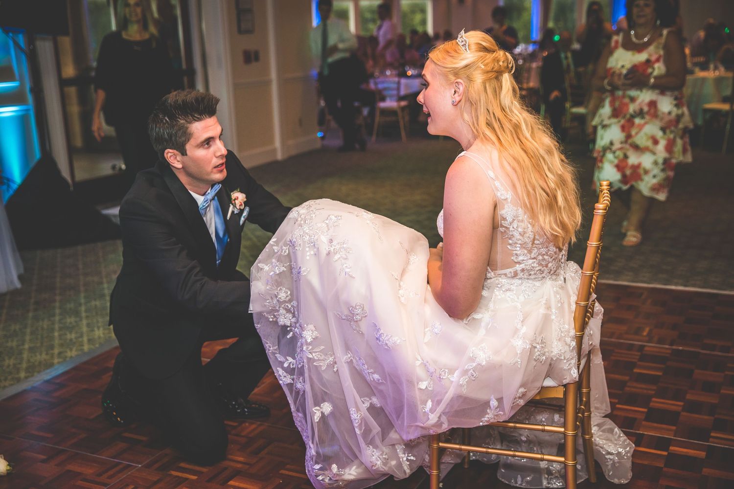 Wedding party celebrates with dancing at a reception with blue lighting.