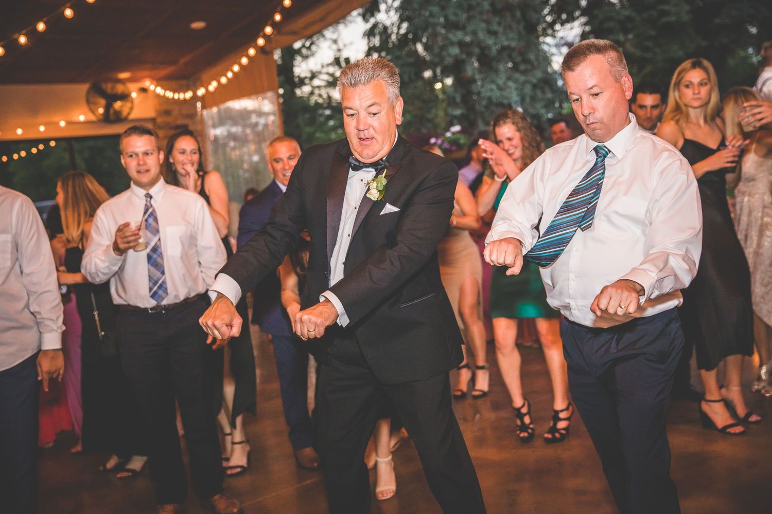 Wedding reception dance floor filled with guests celebrating under ambient lighting.